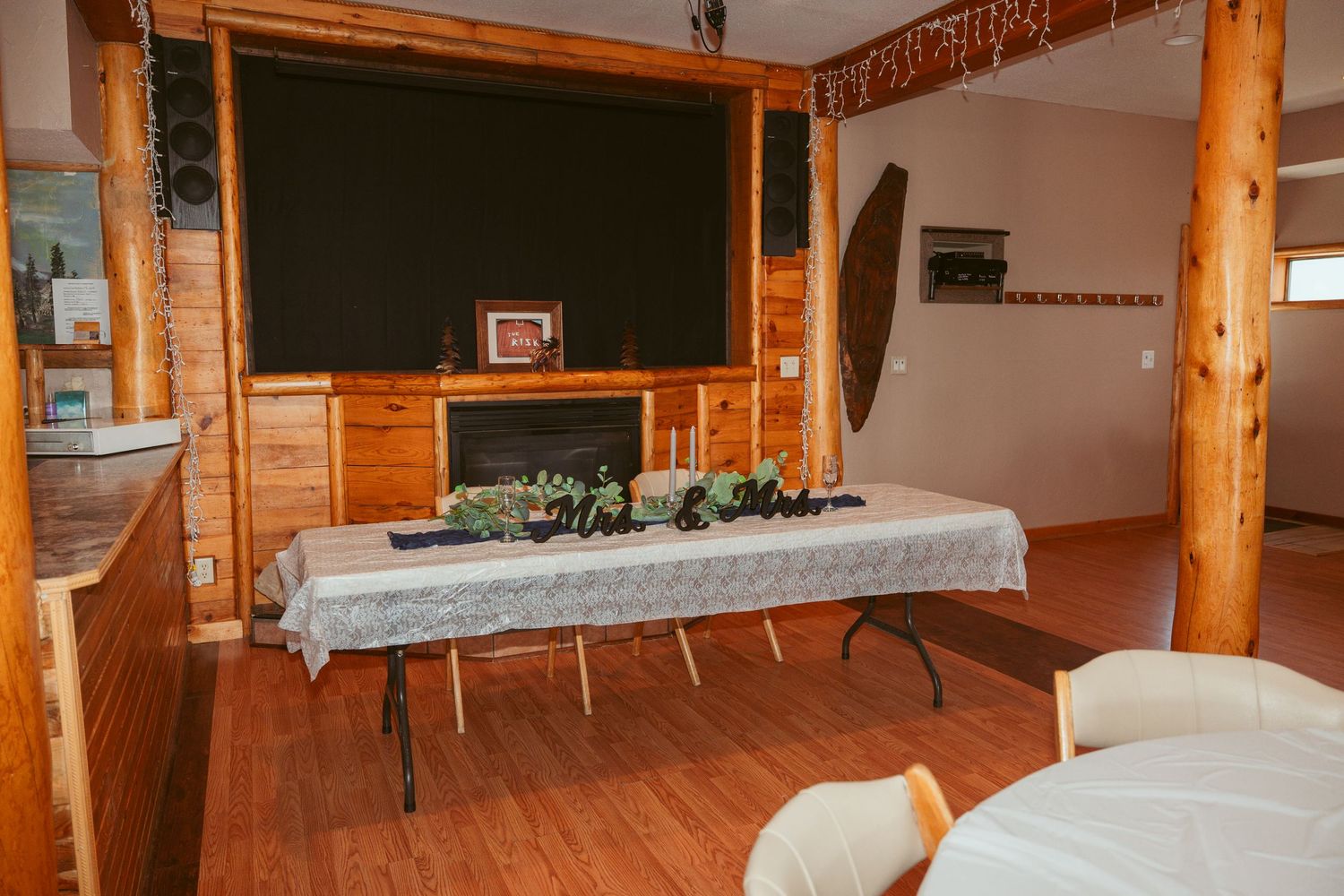 Interior view of a rustic log cabin meeting space with wooden beams and folding tables arranged in rows.