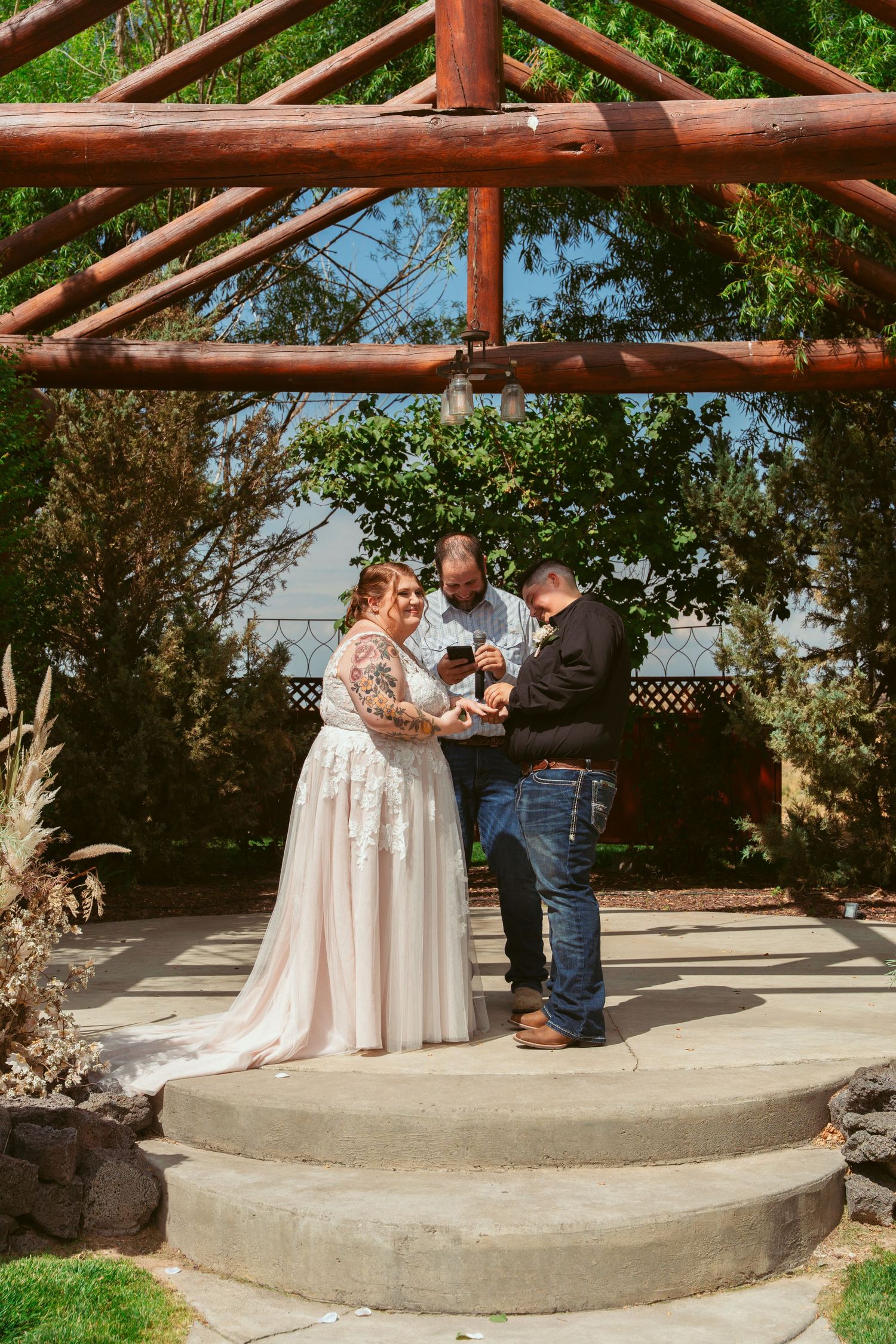 A heartfelt proposal moment unfolds on concrete steps under a wooden pergola in a garden setting.