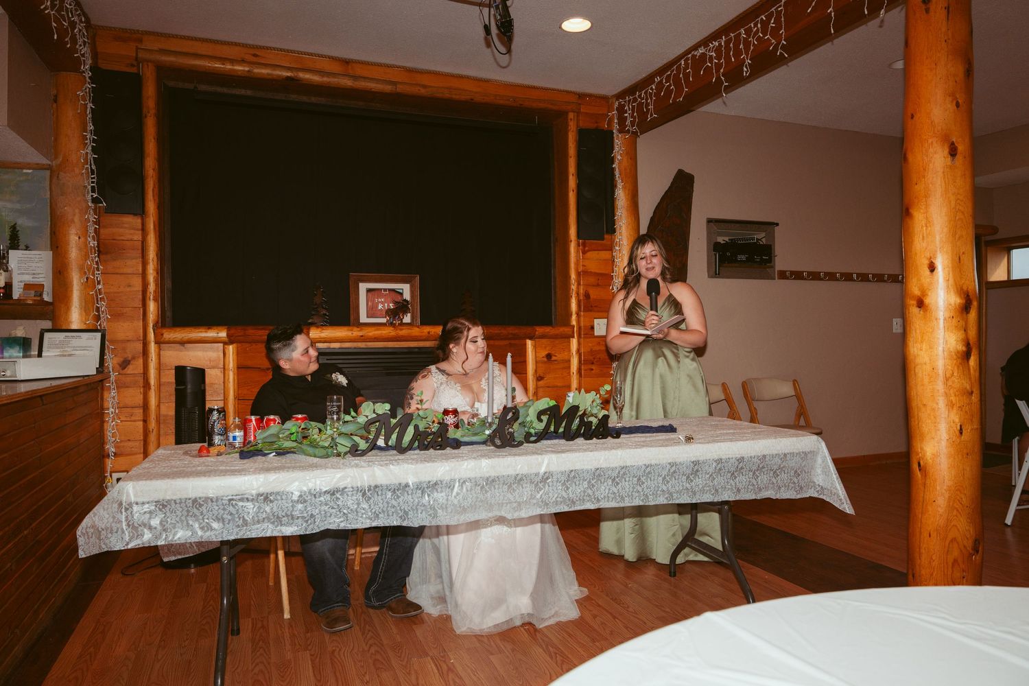 Interior of rustic venue with wooden posts and decorative lighting.