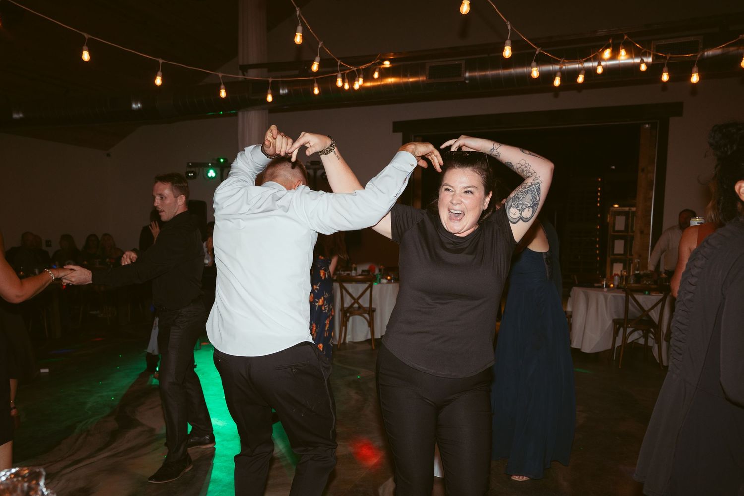 People dancing together in a darkened room with string lights creating a warm atmosphere.