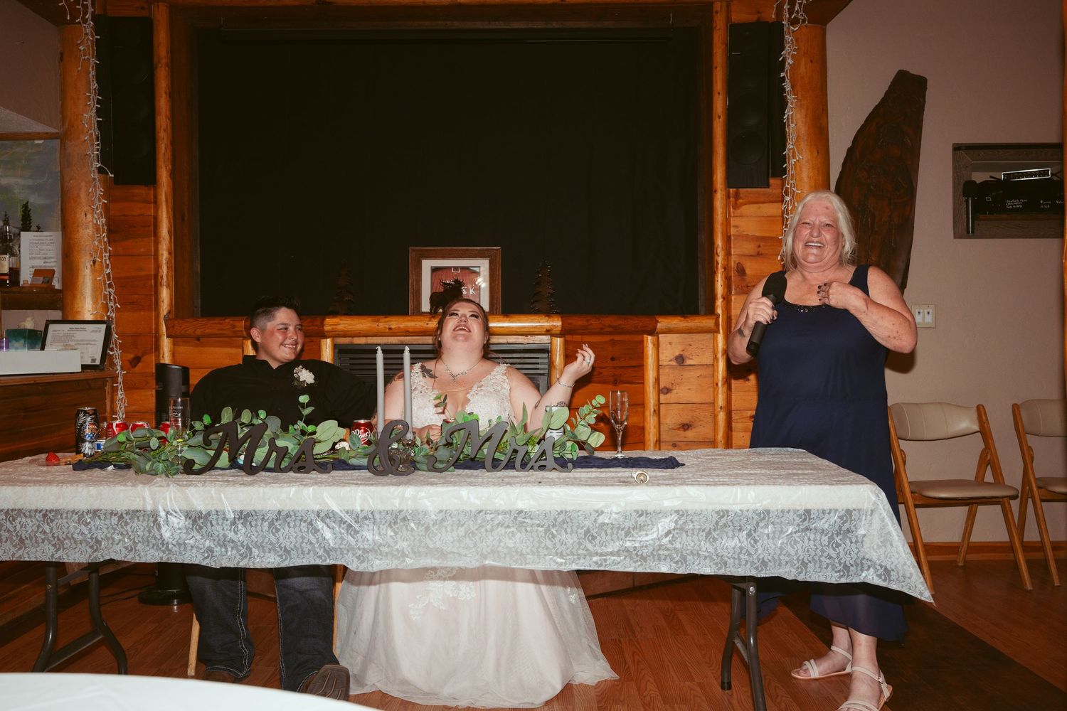 Long banquet tables set up in a wooden lodge for a wedding reception with elegant decorations.