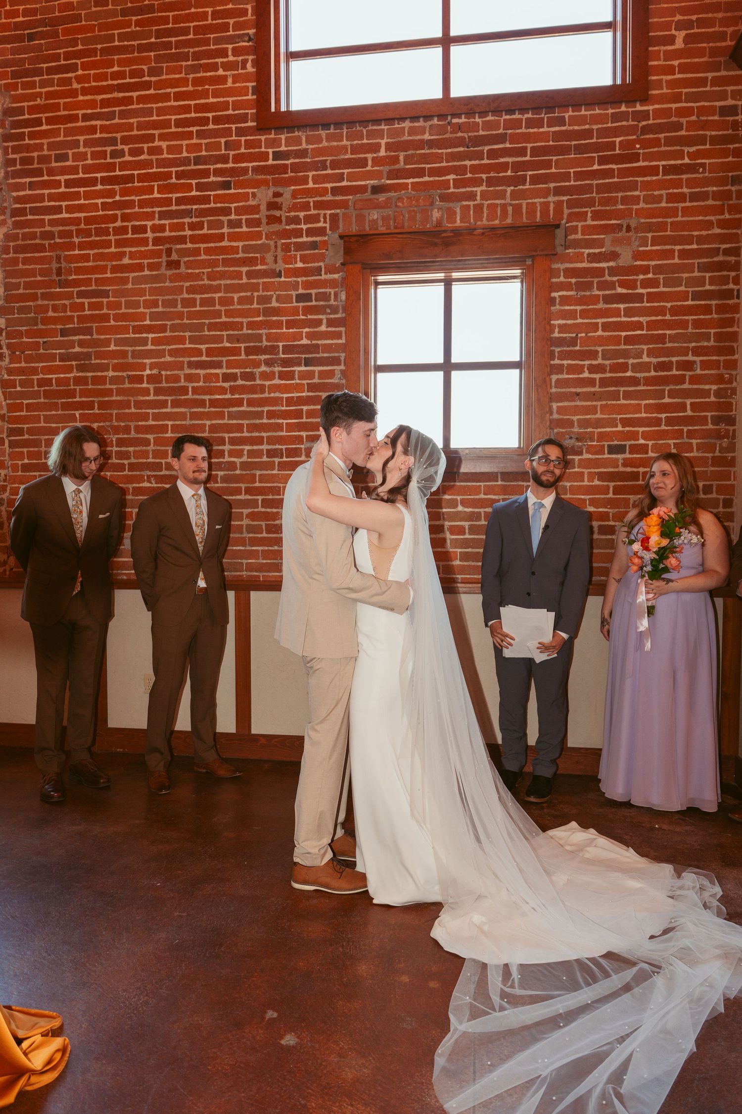 Wedding celebration in a spacious brick venue with flowing white dress and purple bridesmaid gowns.