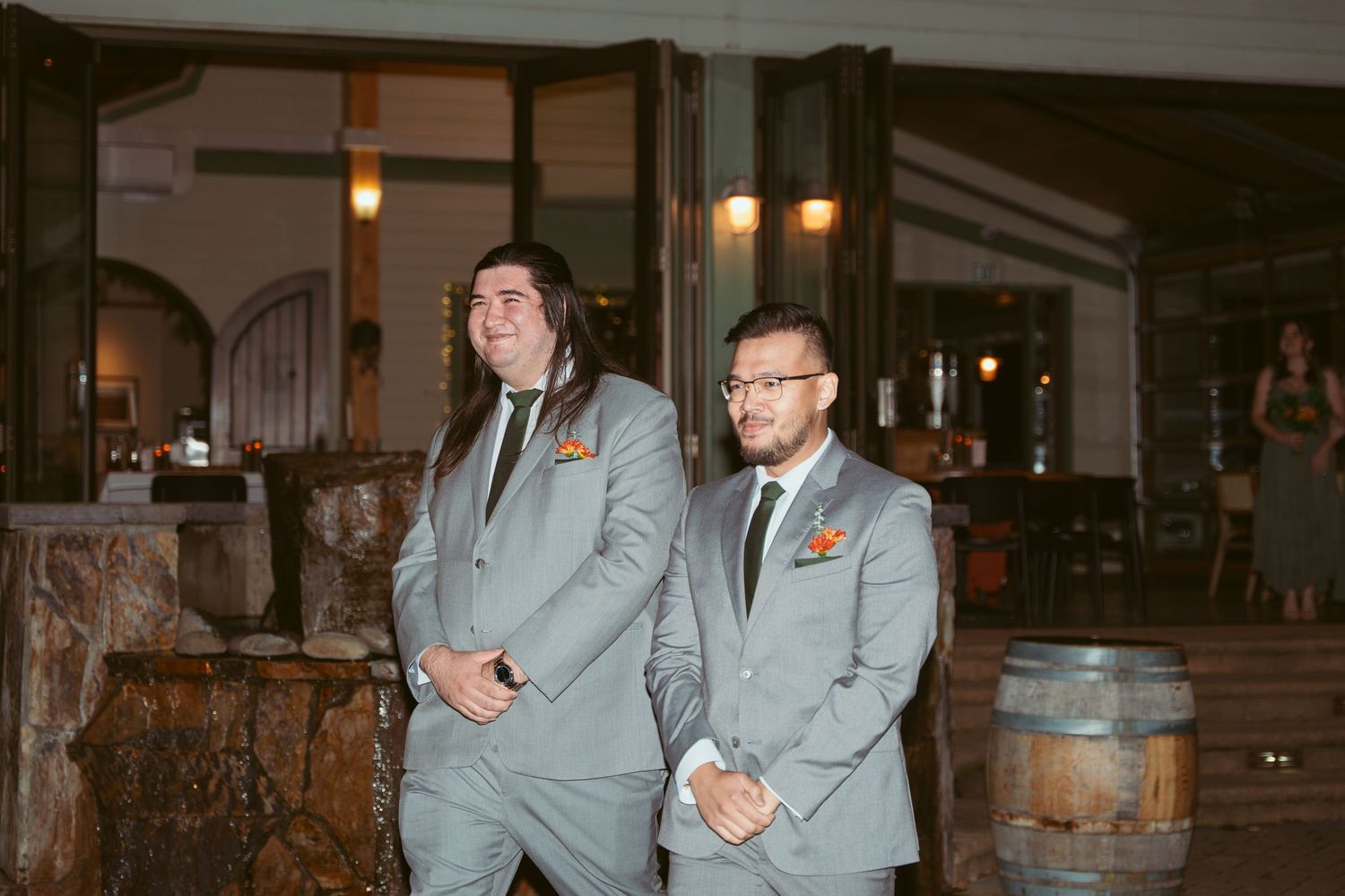 Groomsmen in matching gray suits pose together at an evening event.