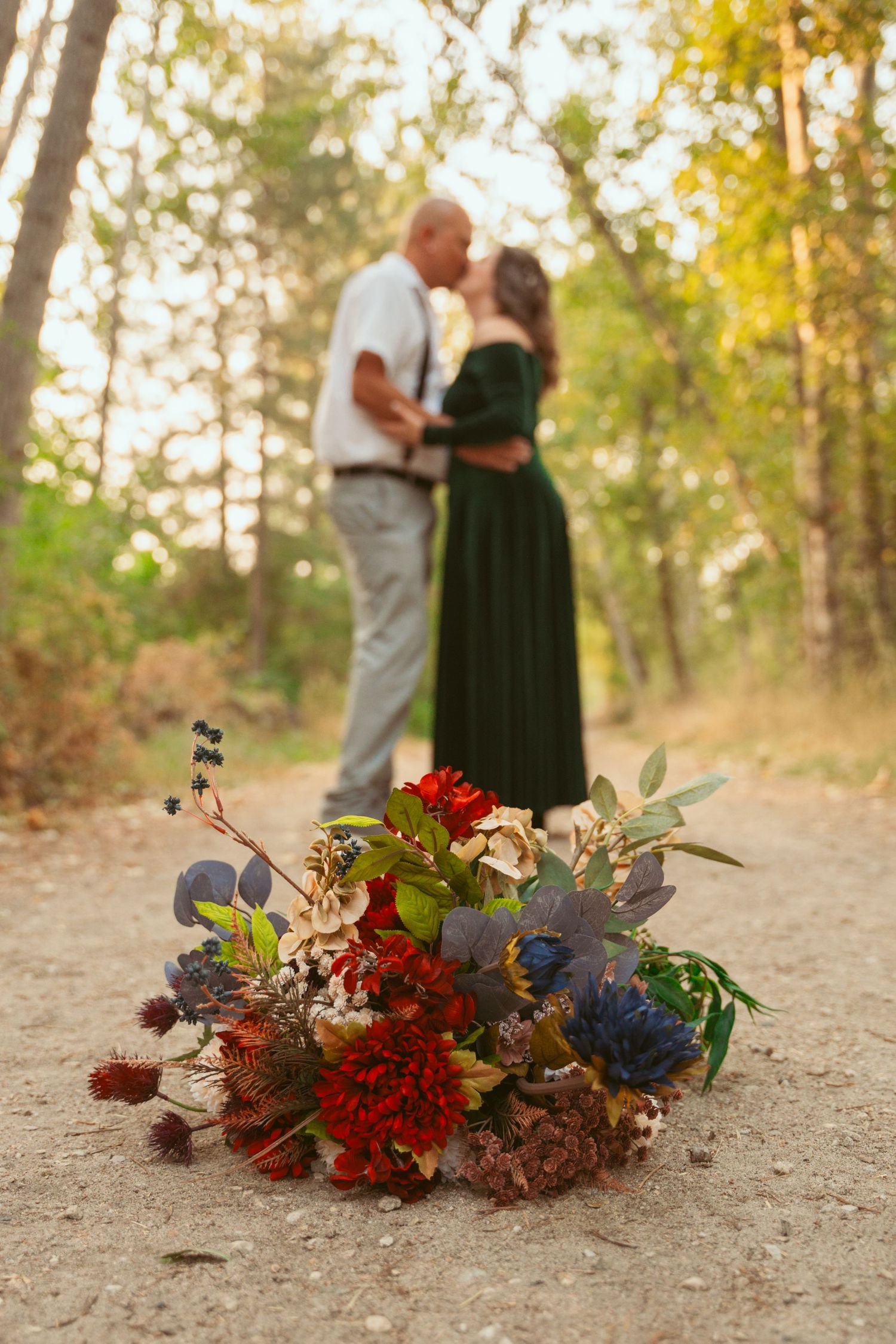 Fall floral arrangement with red blooms and foliage on a dirt path.