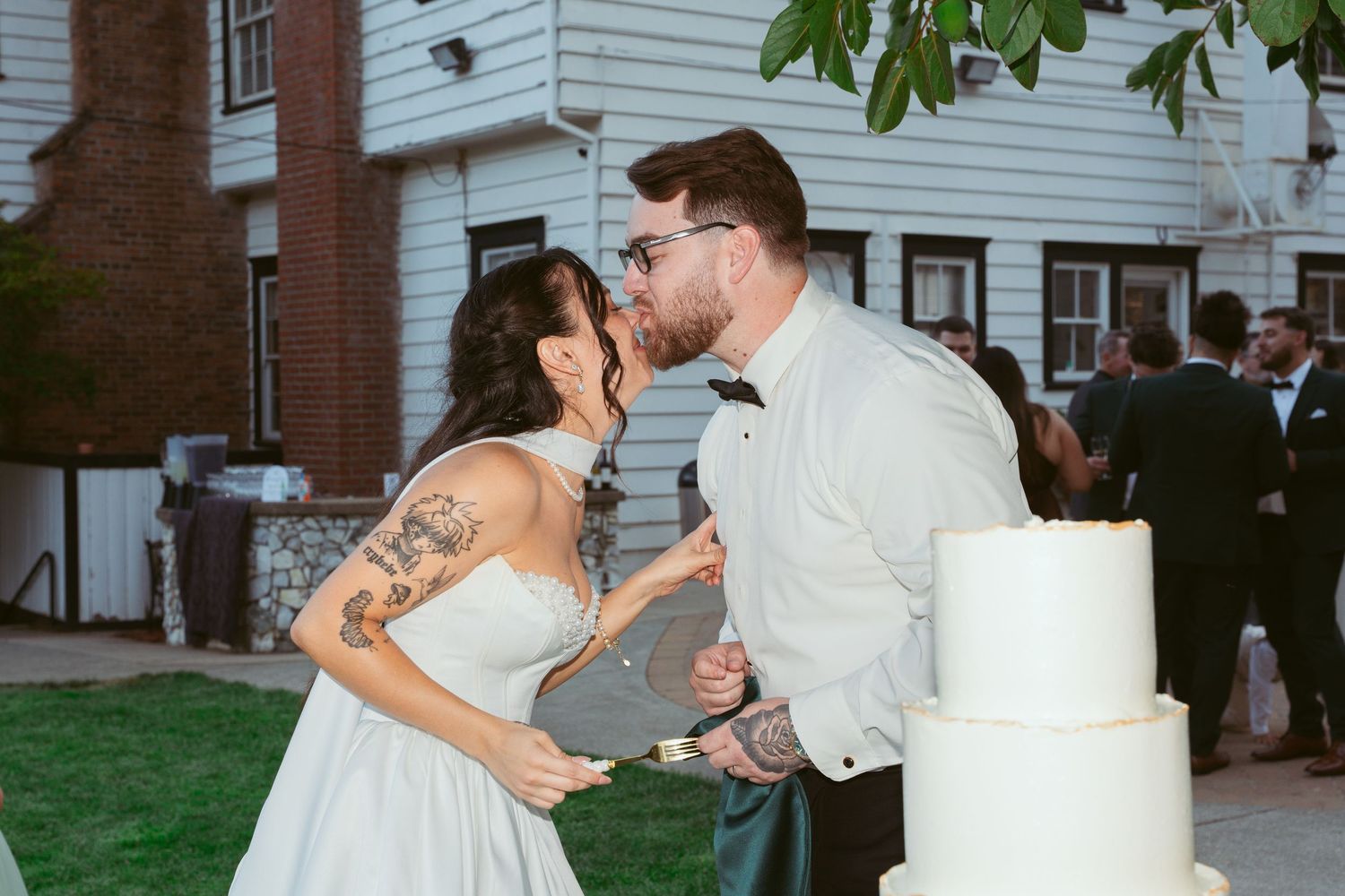 A couple enjoys a fun cake-cutting moment at their outdoor wedding reception.