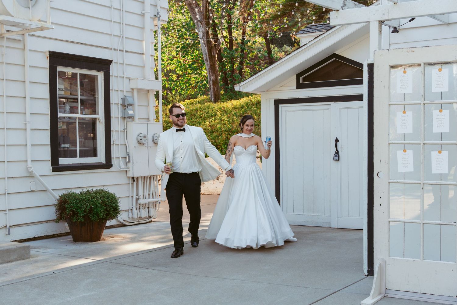 A white clapboard building exterior with wedding decor and string lights creates a romantic atmosphere.