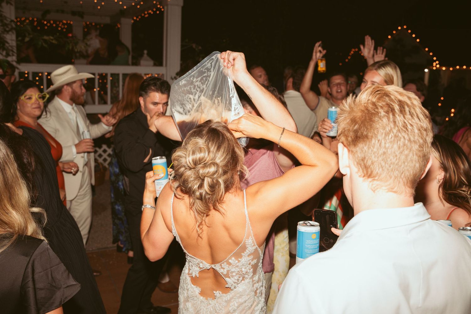 Guests dancing and raising their hands during a lively outdoor wedding reception.