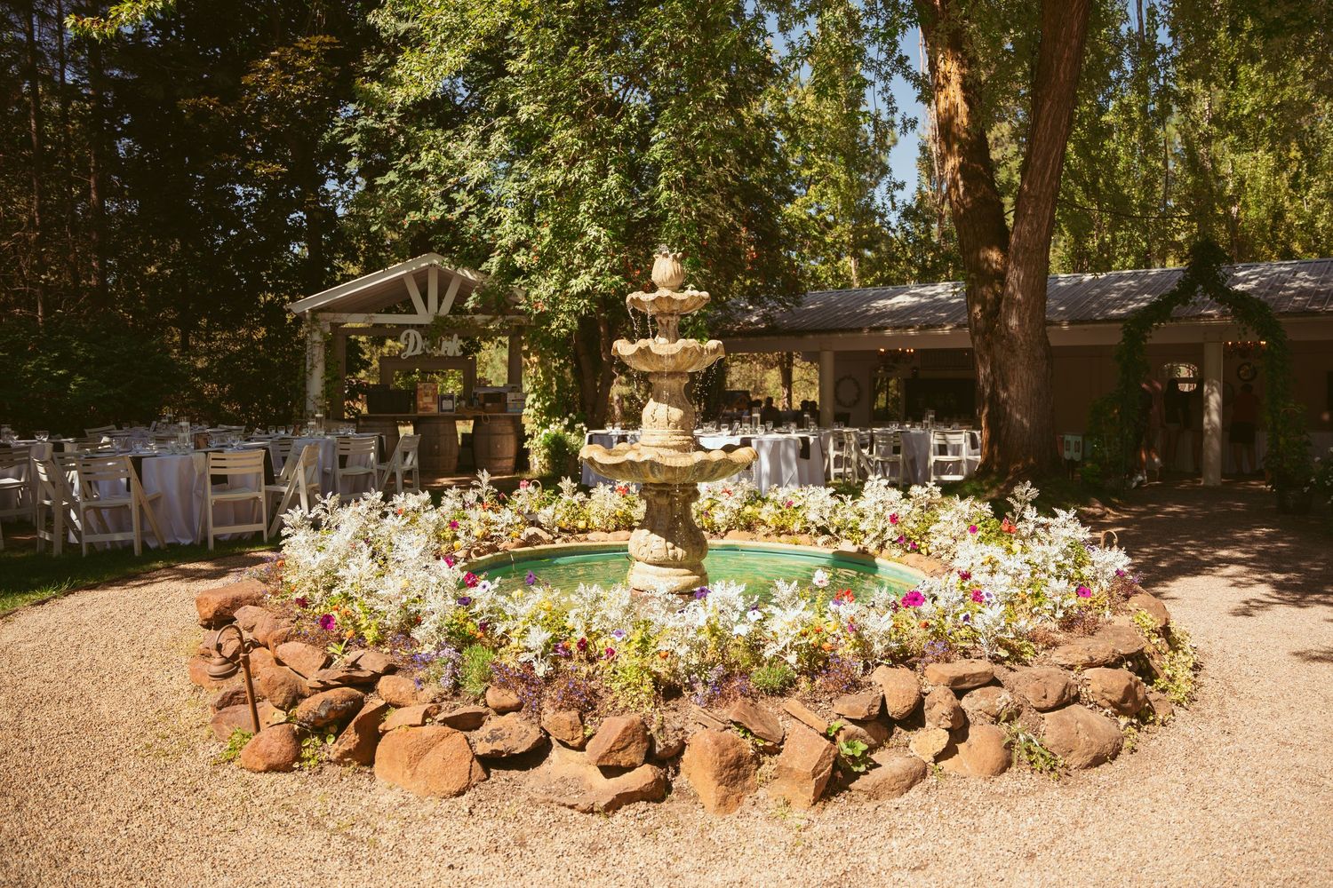 A panoramic view of a garden pathway with terracotta pots and colorful flowers in a shaded outdoor setting.