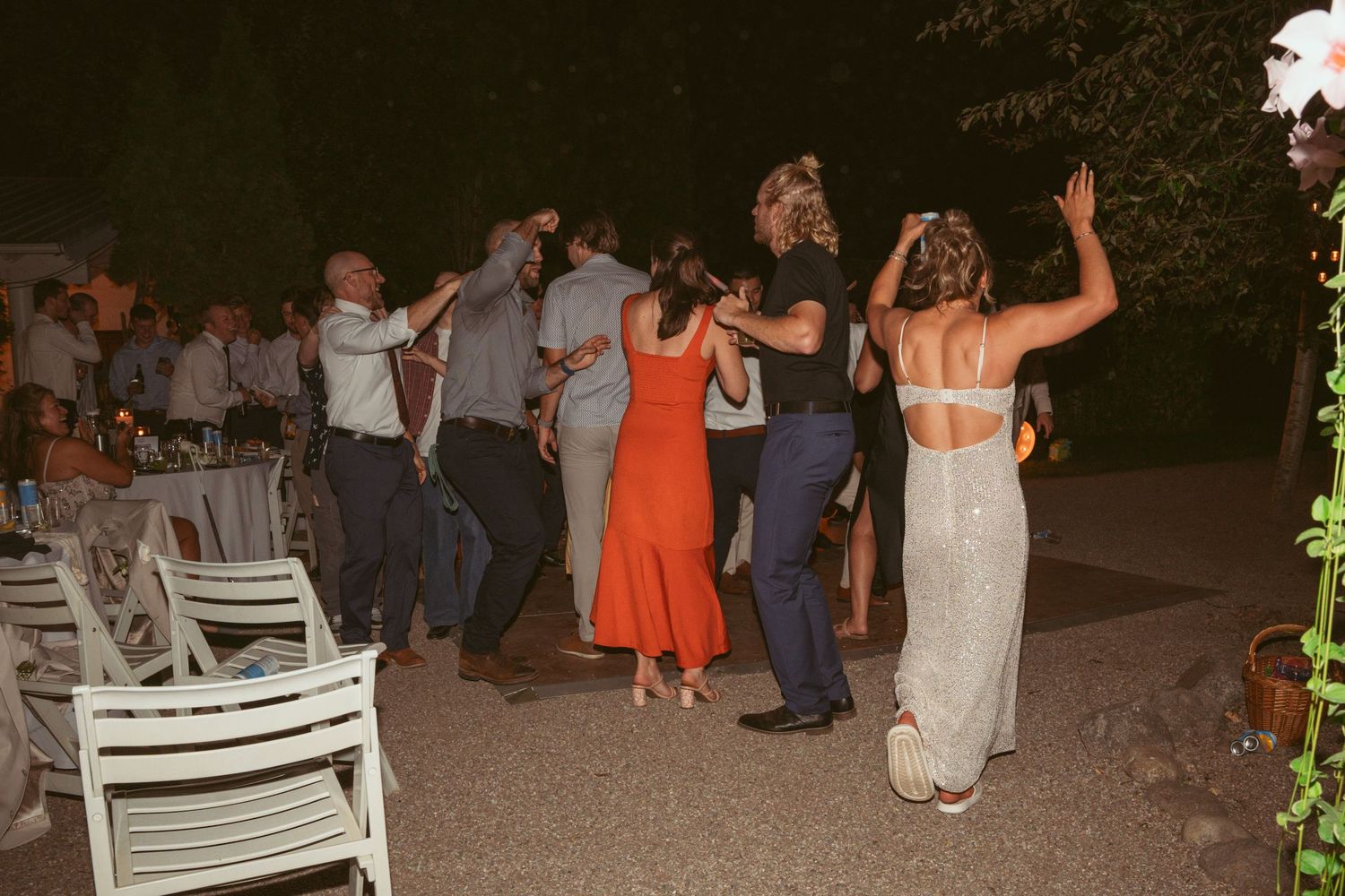 Wedding guests dance and celebrate on an outdoor dance floor at a nighttime reception.