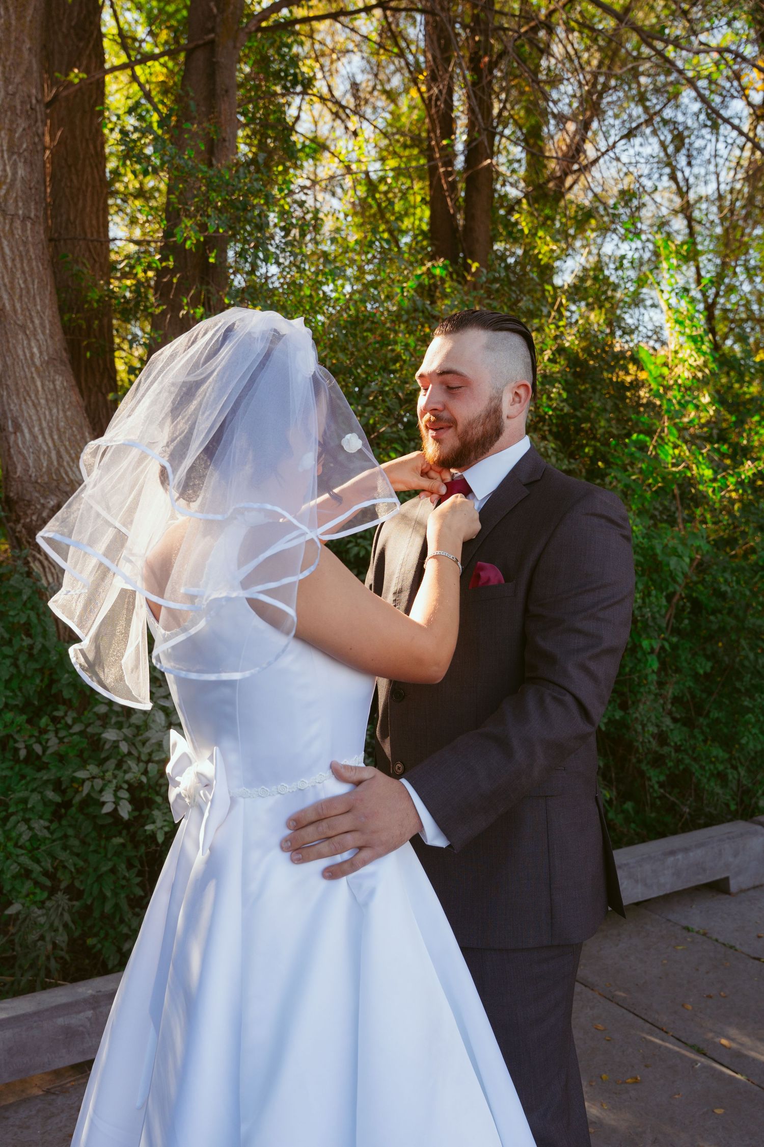 A sweet wedding moment captured on a wooden deck with natural forest backdrop.