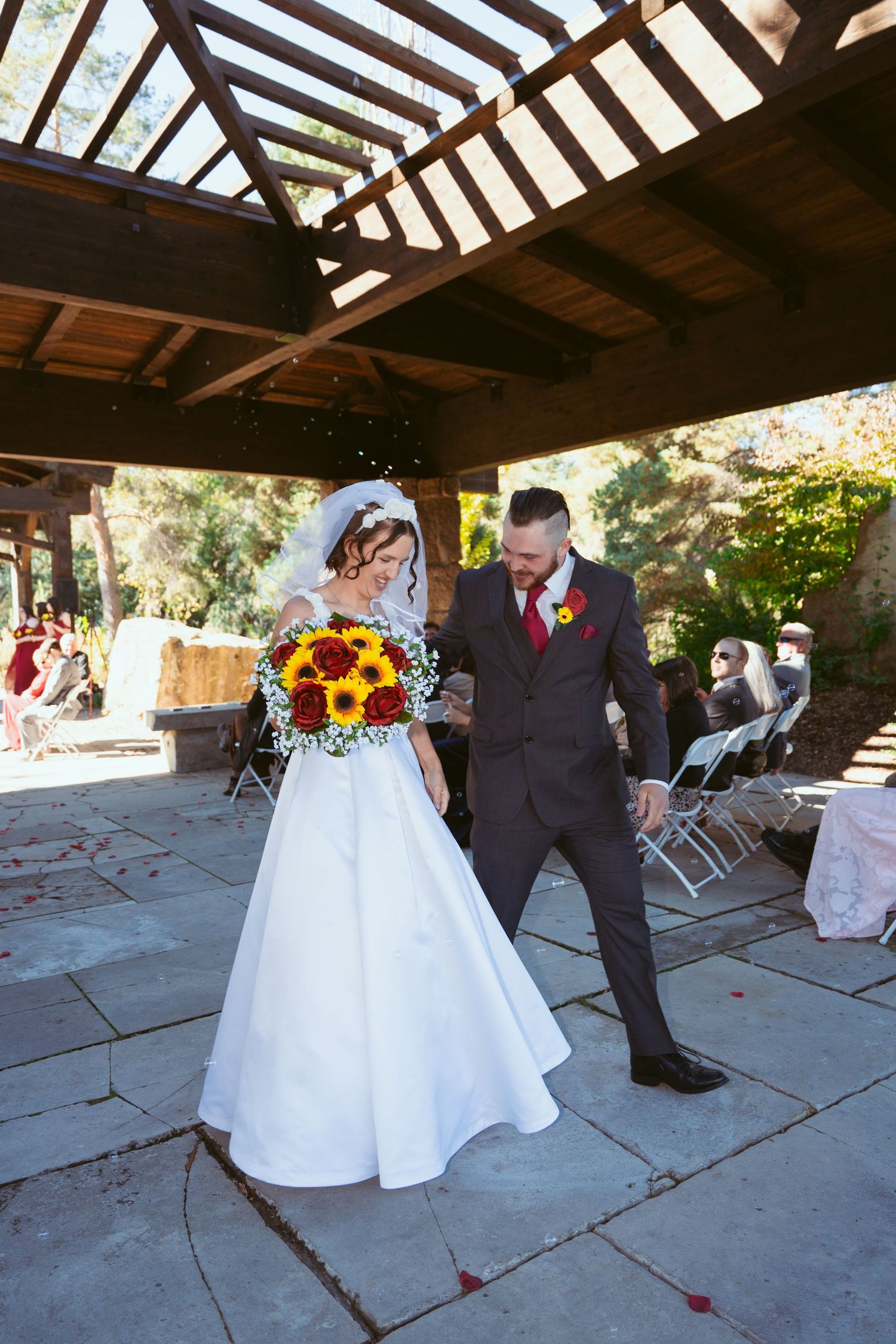 Couple in wedding attire sharing a dance moment under a covered outdoor venue.