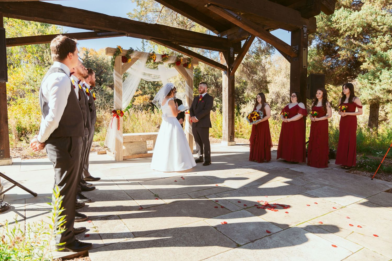 Panoramic view of wedding ceremony under wooden pavilion with autumn scenery.