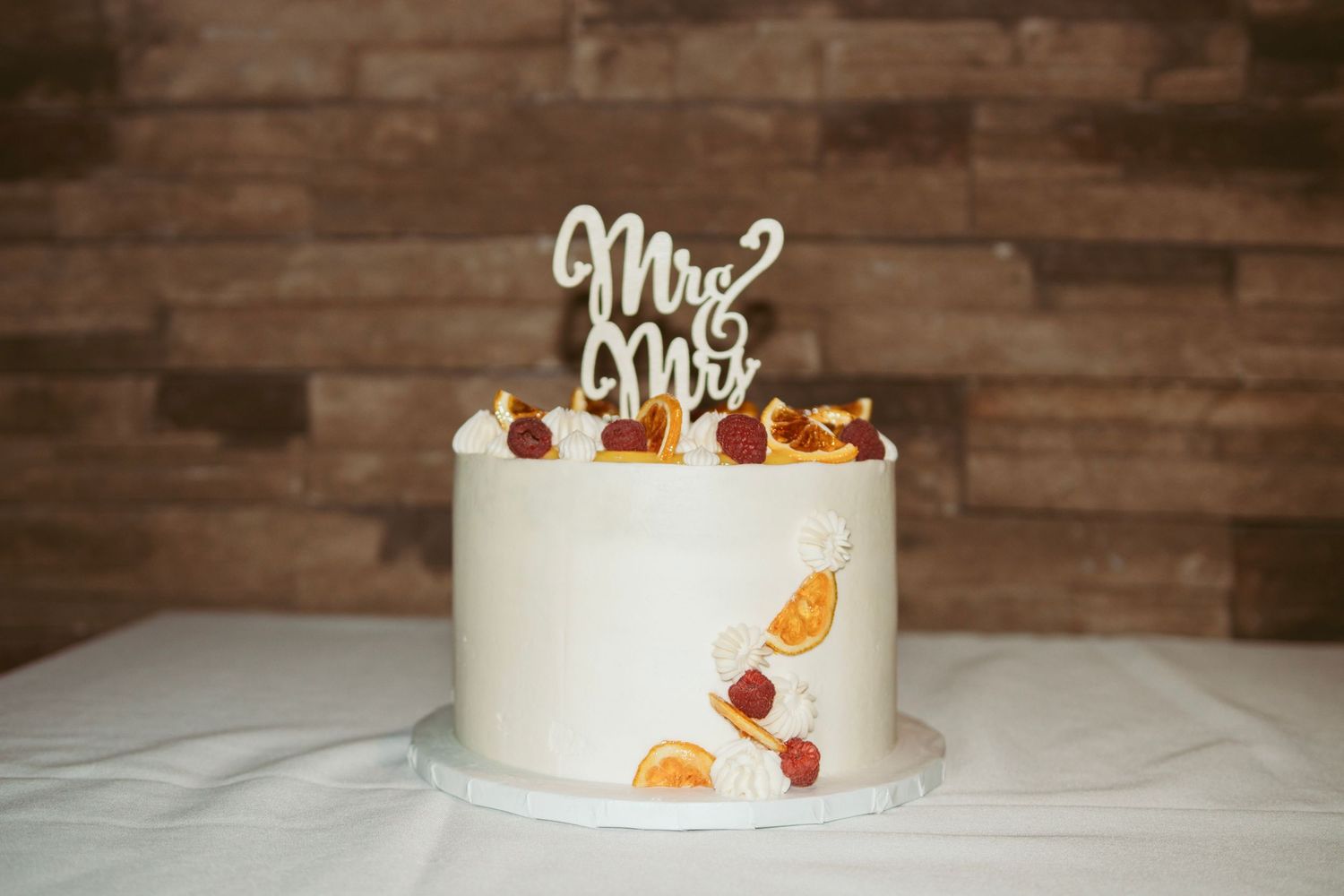 A white wedding cake decorated with dried citrus slices and a 'Mr & Mrs' topper.
