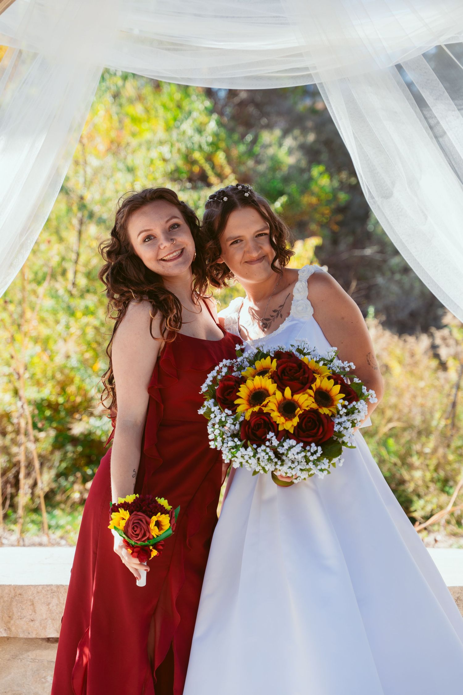 Joyful wedding moment captured under white draped pavilion with sunflower bouquets.