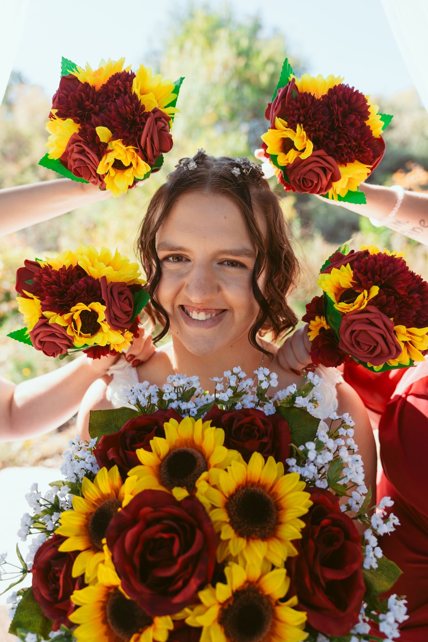 Close-up floral arrangement with burgundy roses, sunflowers and baby's breath in natural lighting.