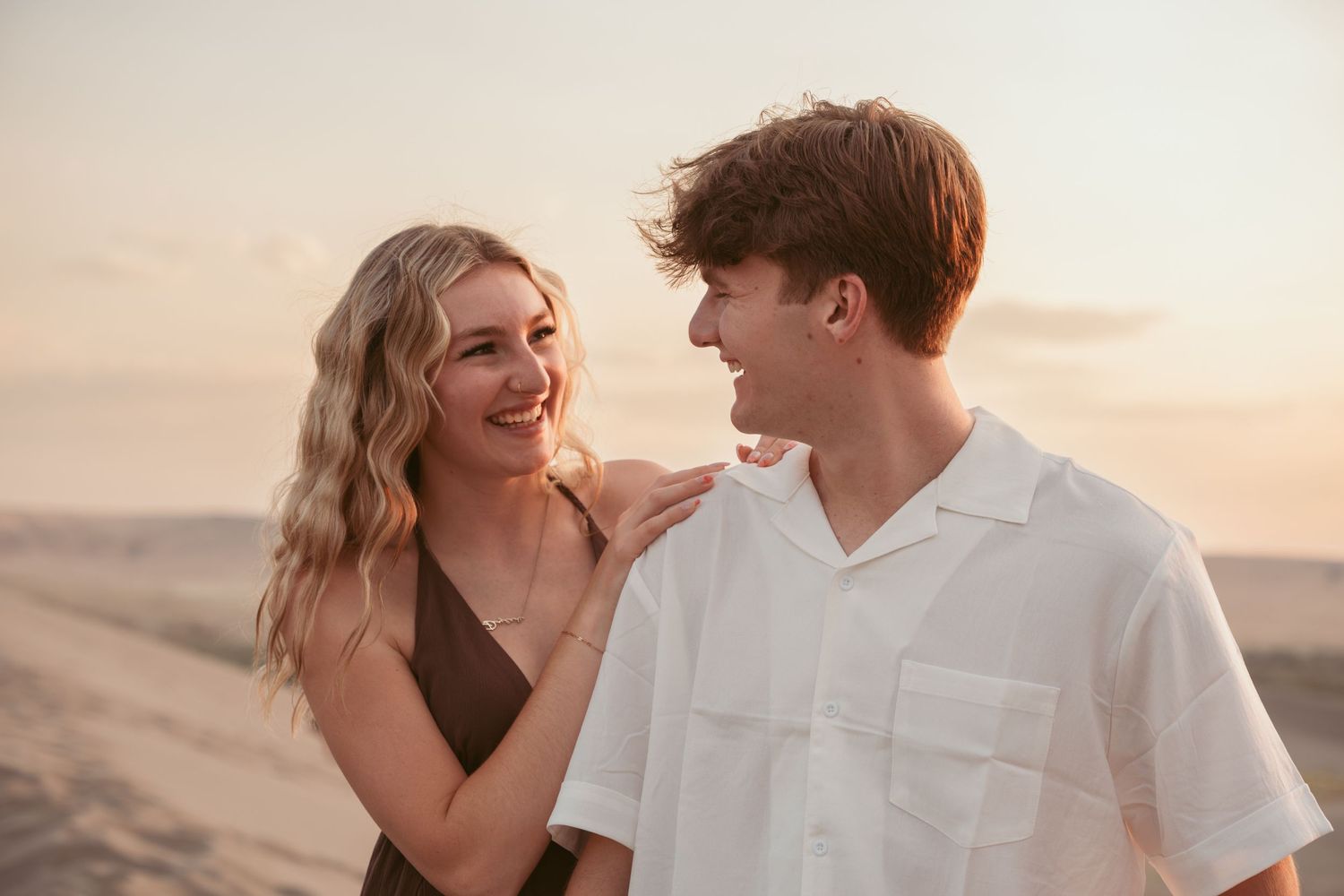 A couple laughs together during a desert photoshoot at dusk.