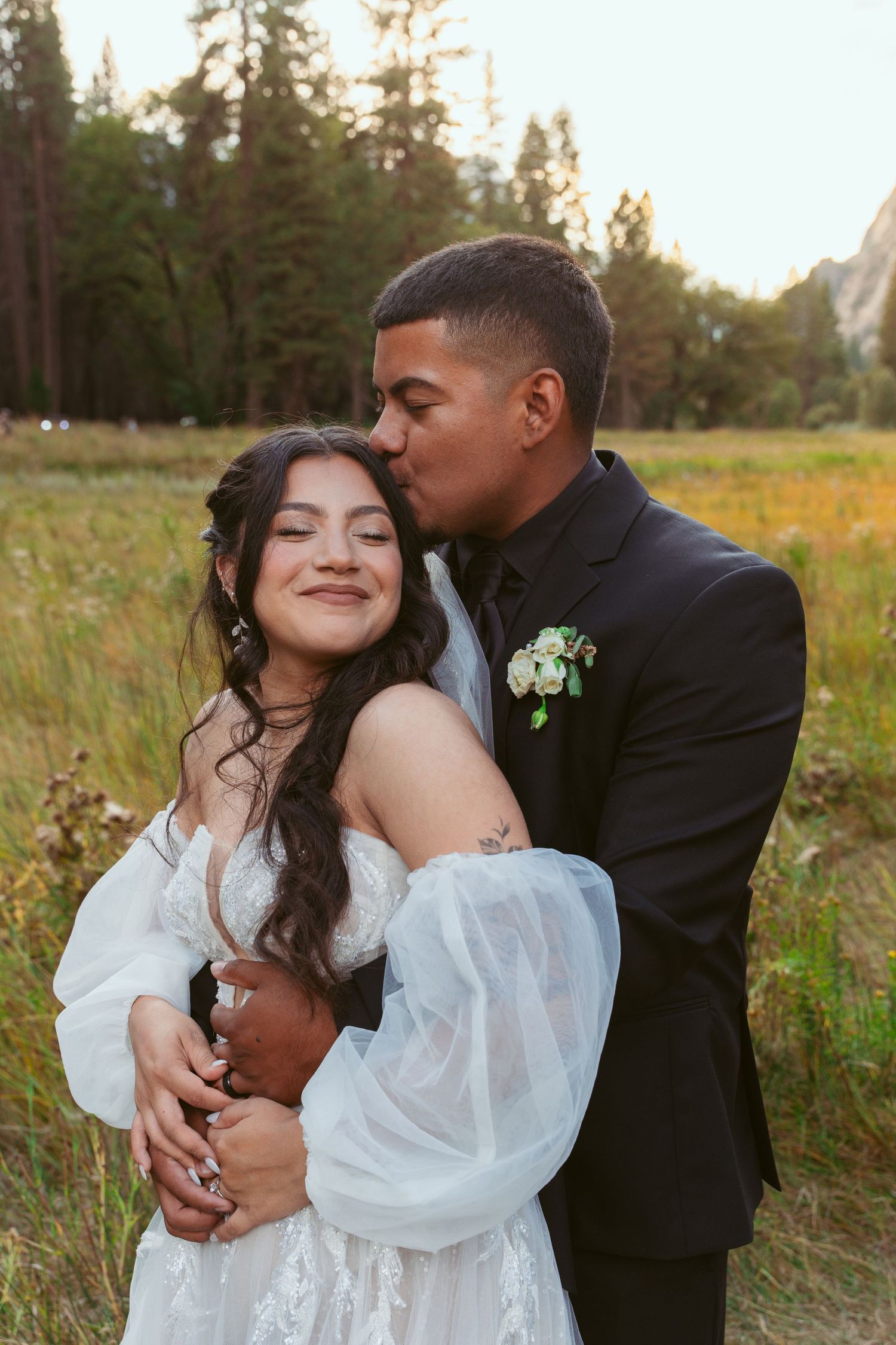 Romantic wedding portrait in golden meadow with Yosemite's granite peaks behind.