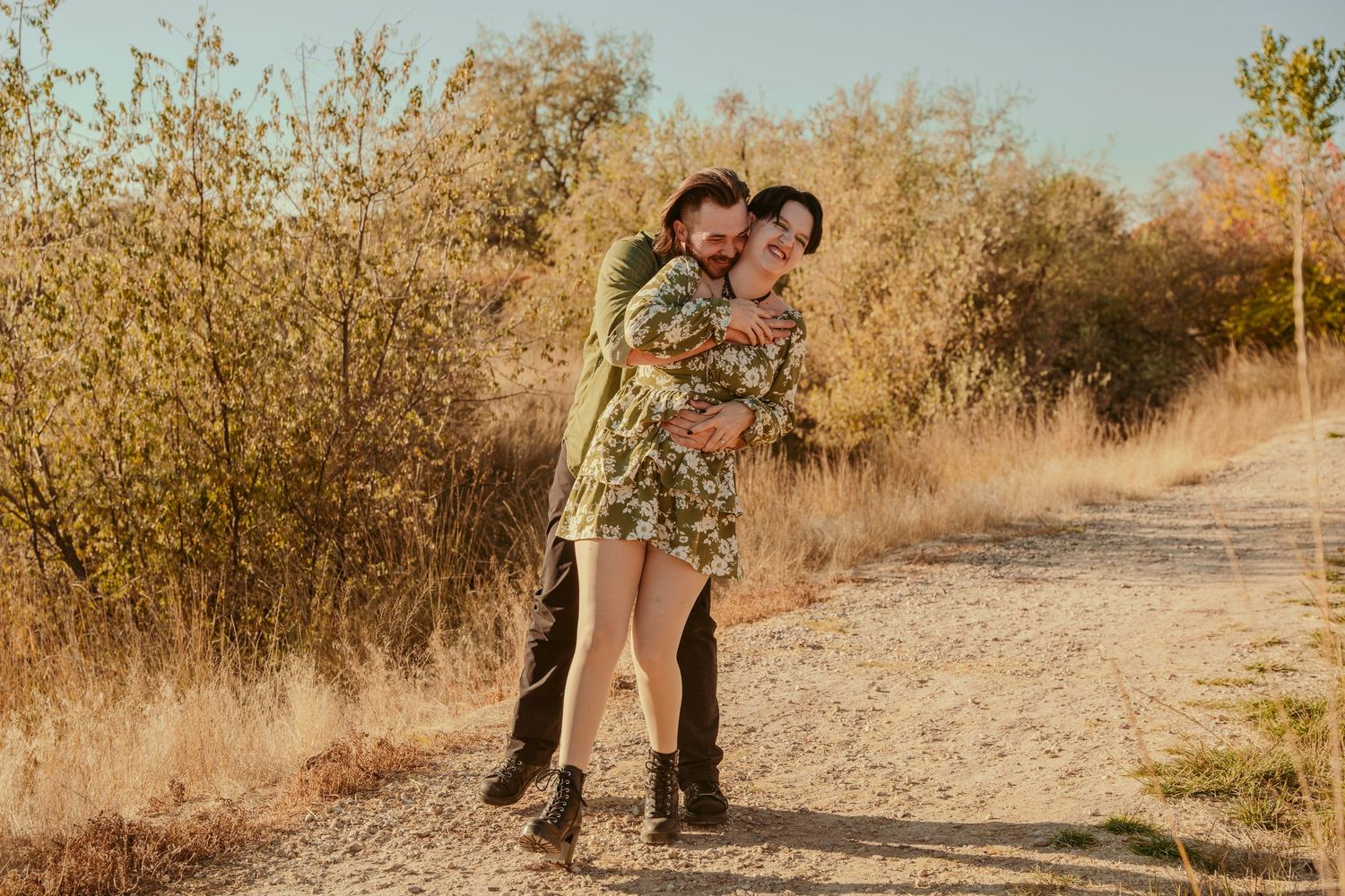 A couple embraces while dancing together on a desert path during a sunset photoshoot.