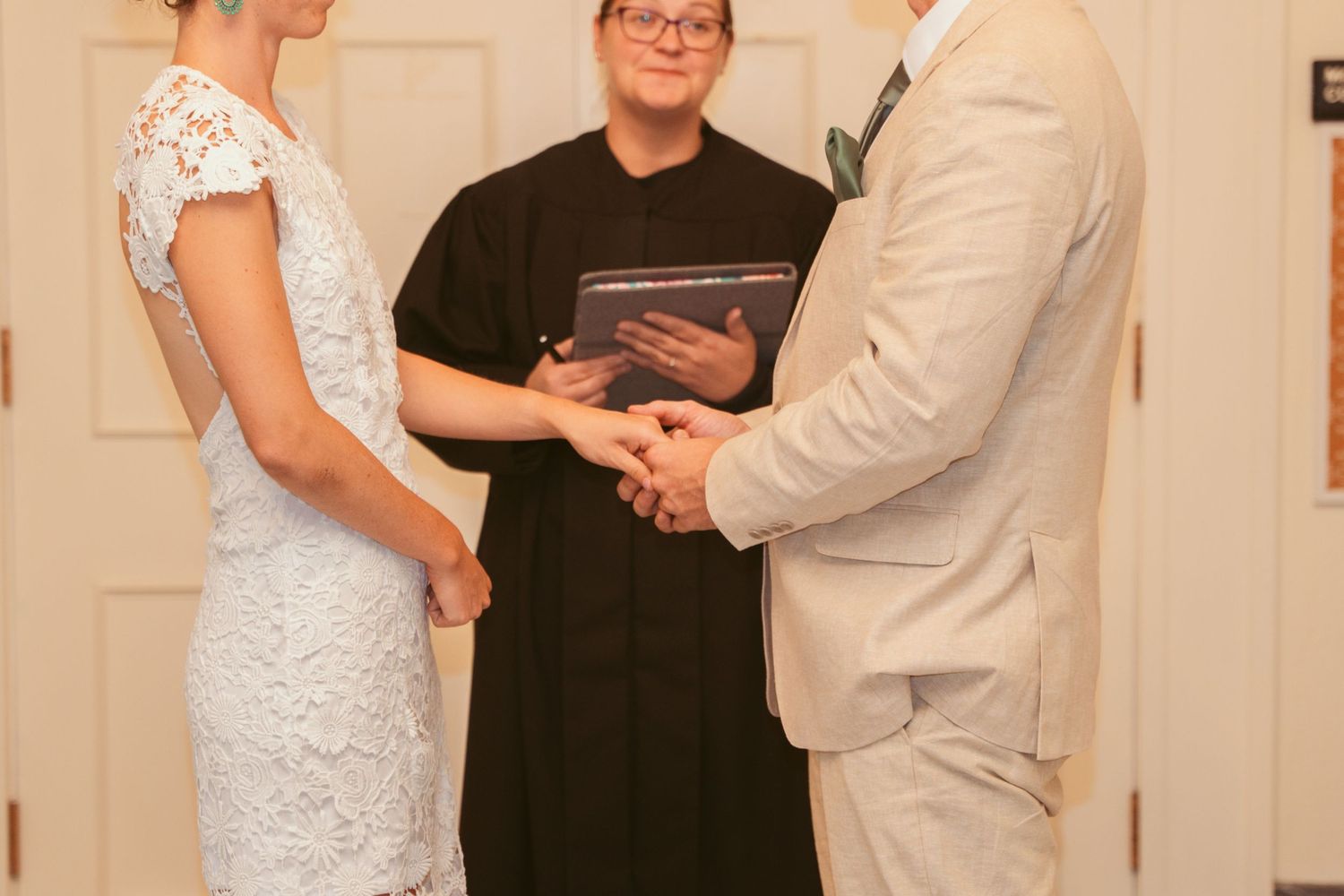 A wedding ceremony with participants gathered in an elegant indoor space with white columns.