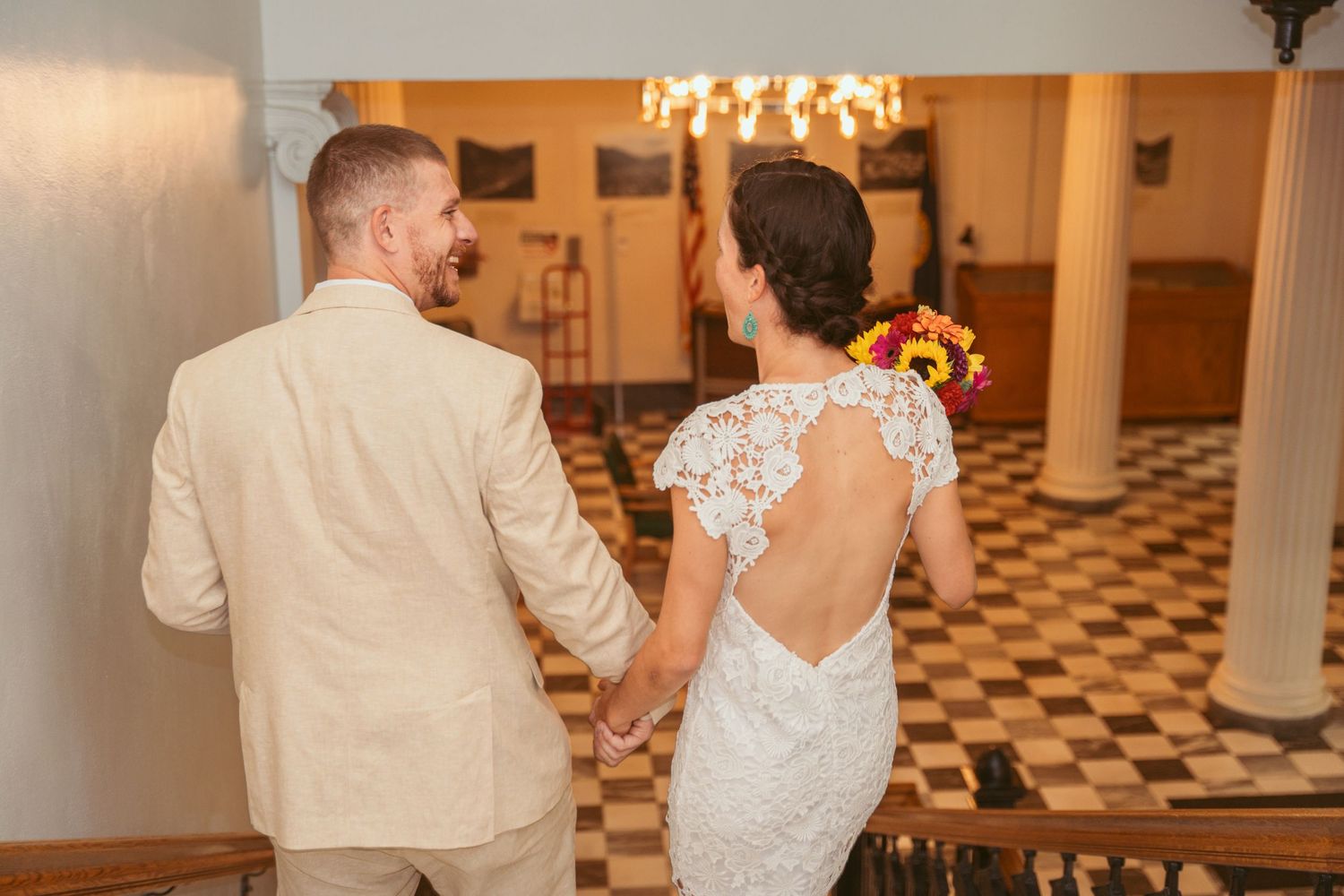 Bride and groom dancing together in a classic ballroom with white pillars.