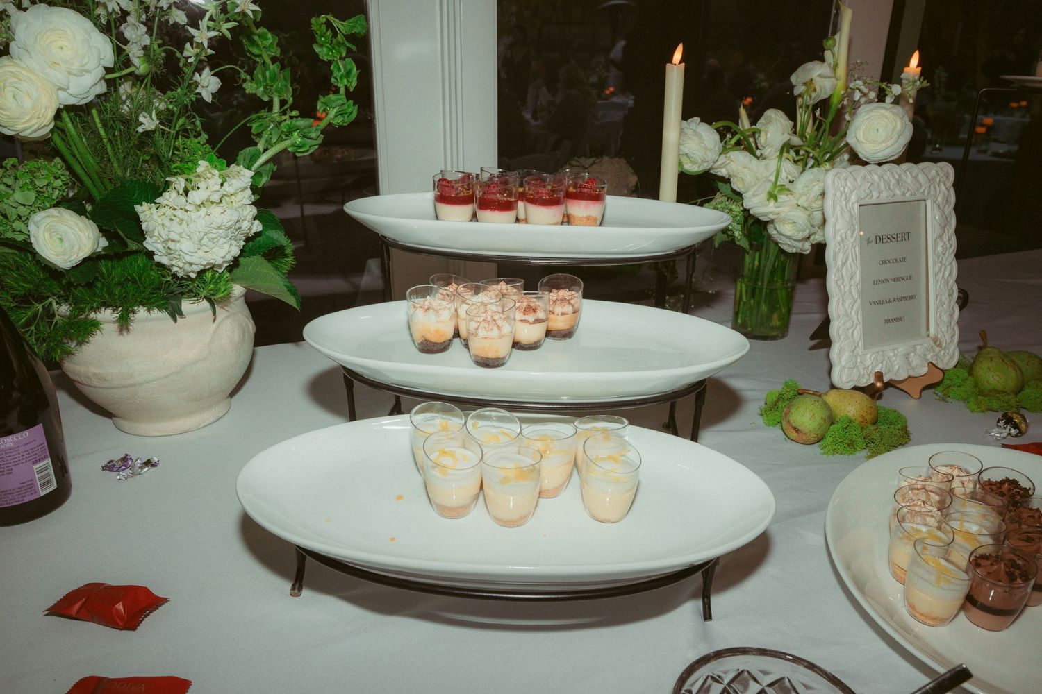 Elegant dessert table with white floral arrangements and candles on display.