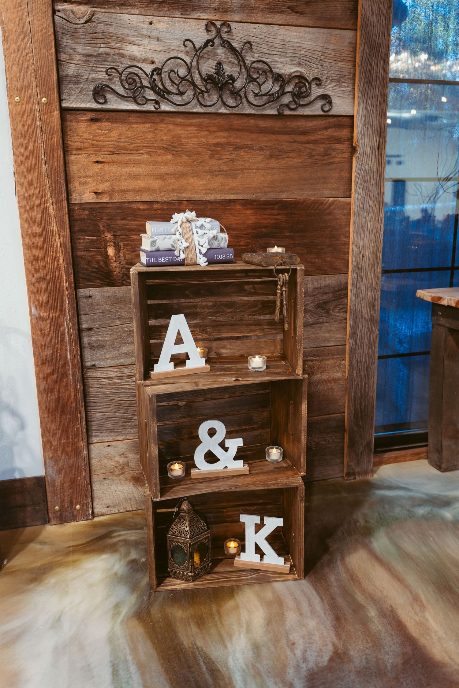 Rustic wooden crates stacked vertically displaying decorative letters A & K with candles and ornamental details.