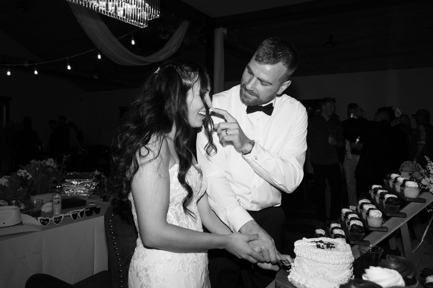 A couple playfully shares their first bite of wedding cake at an evening reception.