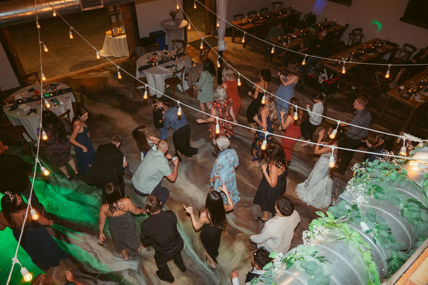 Overhead shot of a lively dance floor with colored lighting and hanging string lights.
