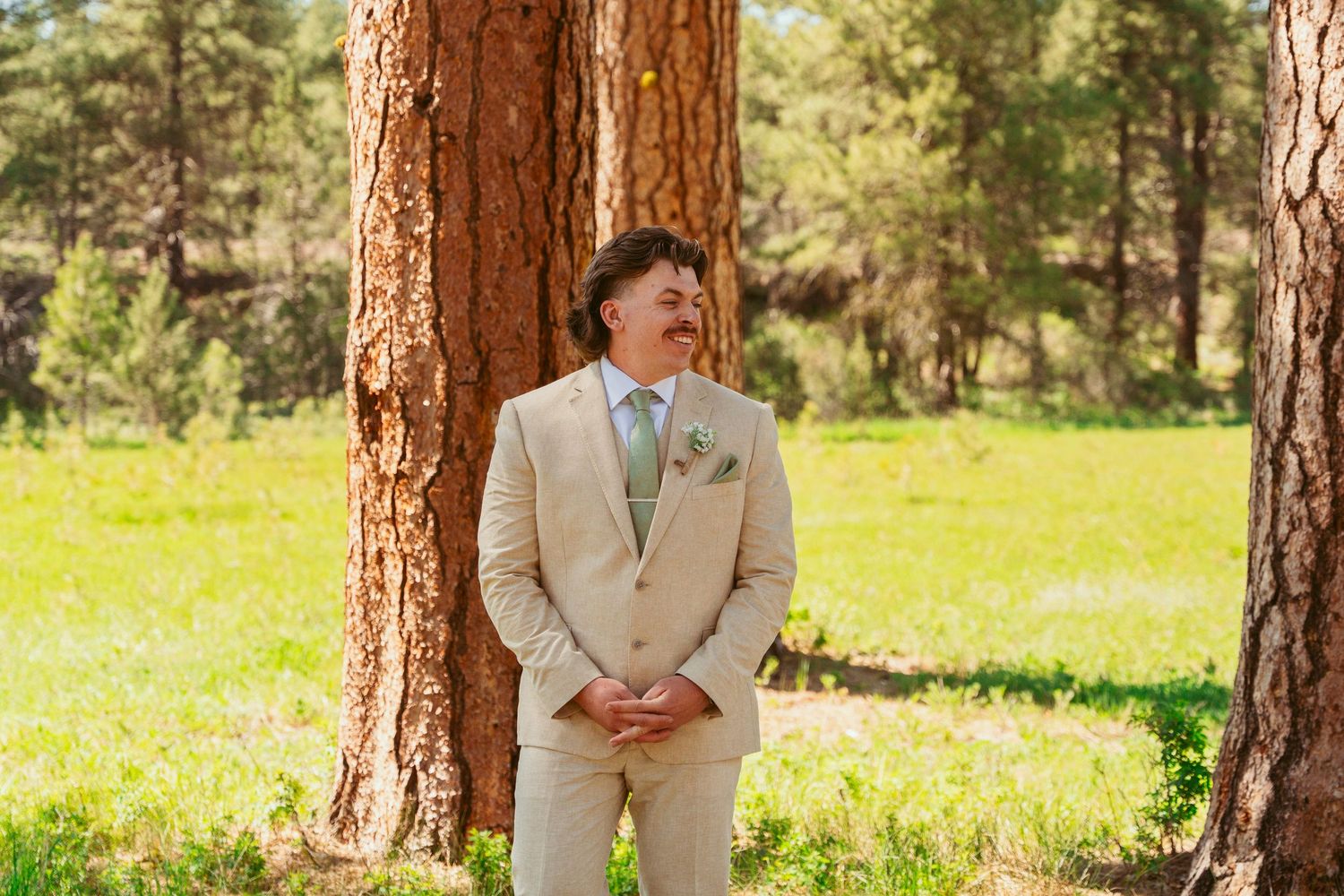 An emotional wedding first look sequence set among towering ponderosa pines in a natural meadow setting.