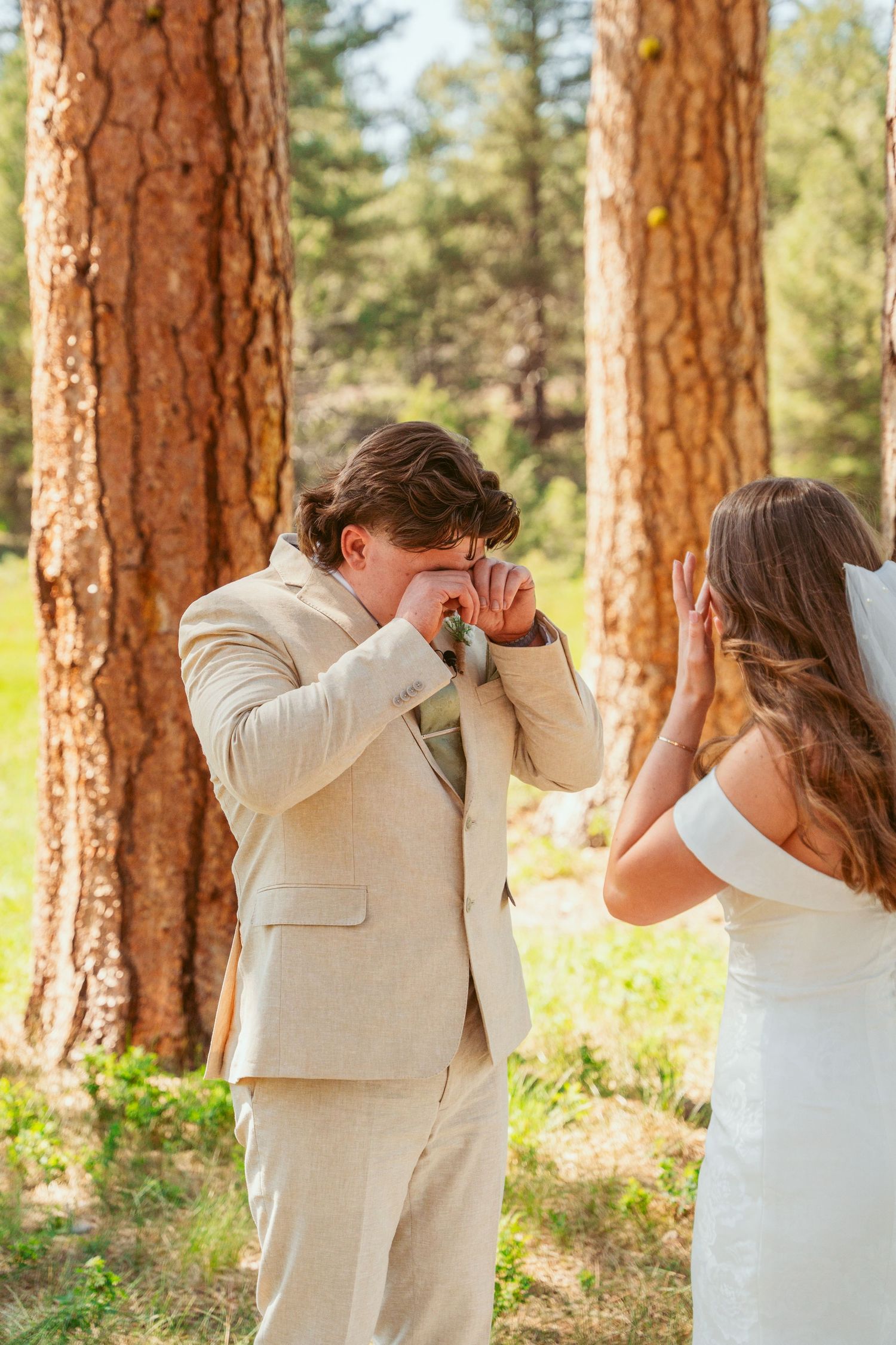 Candid reactions captured during a wedding first look moment in a sunlit forest setting.