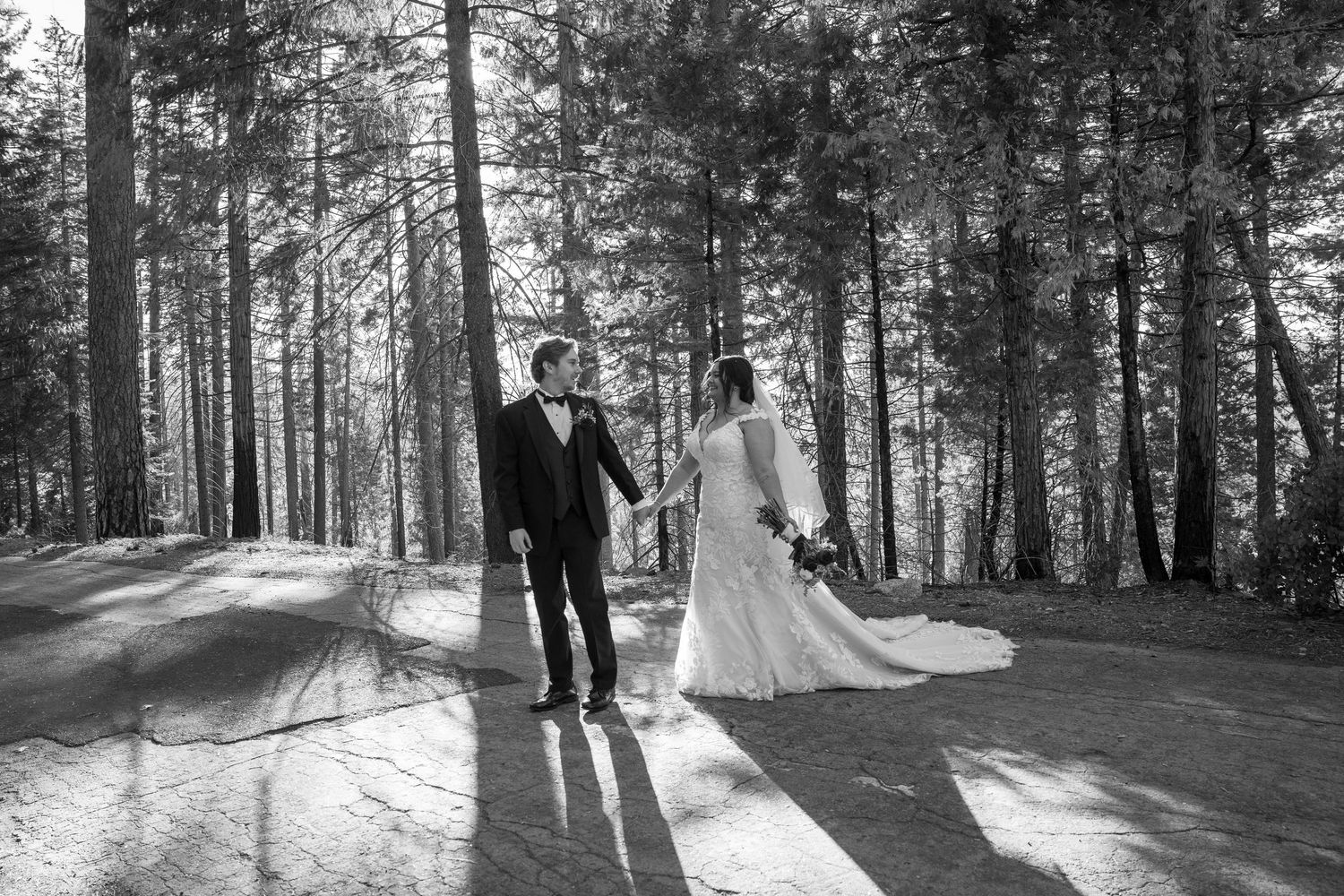 Black and white wedding photos captured in a serene forest setting with dramatic lighting.