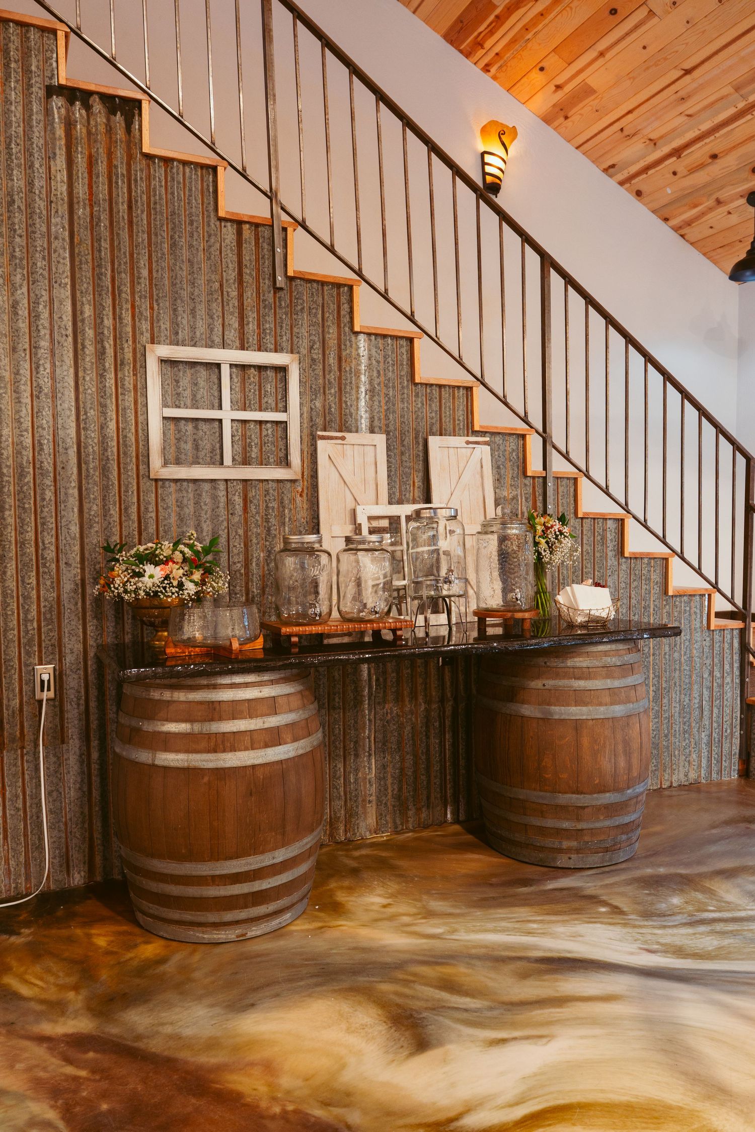 Rustic venue interior with wooden barrel decor and metal corrugated wall details.