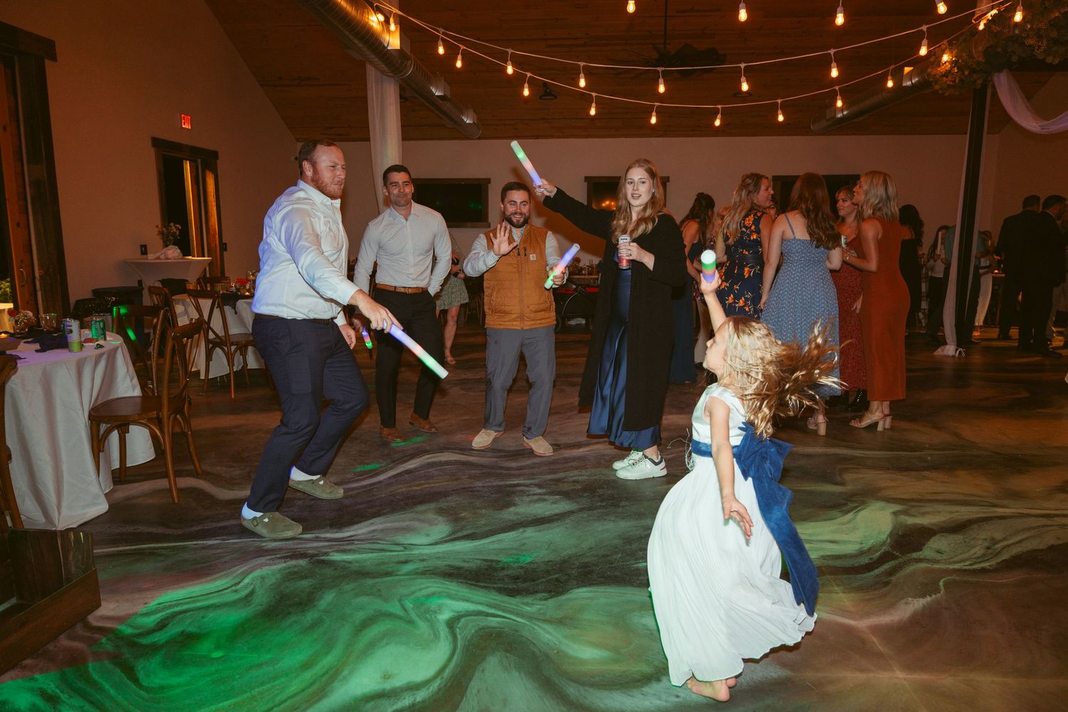 Wedding party dancing with light sabers creates colorful reflections on the dance floor.