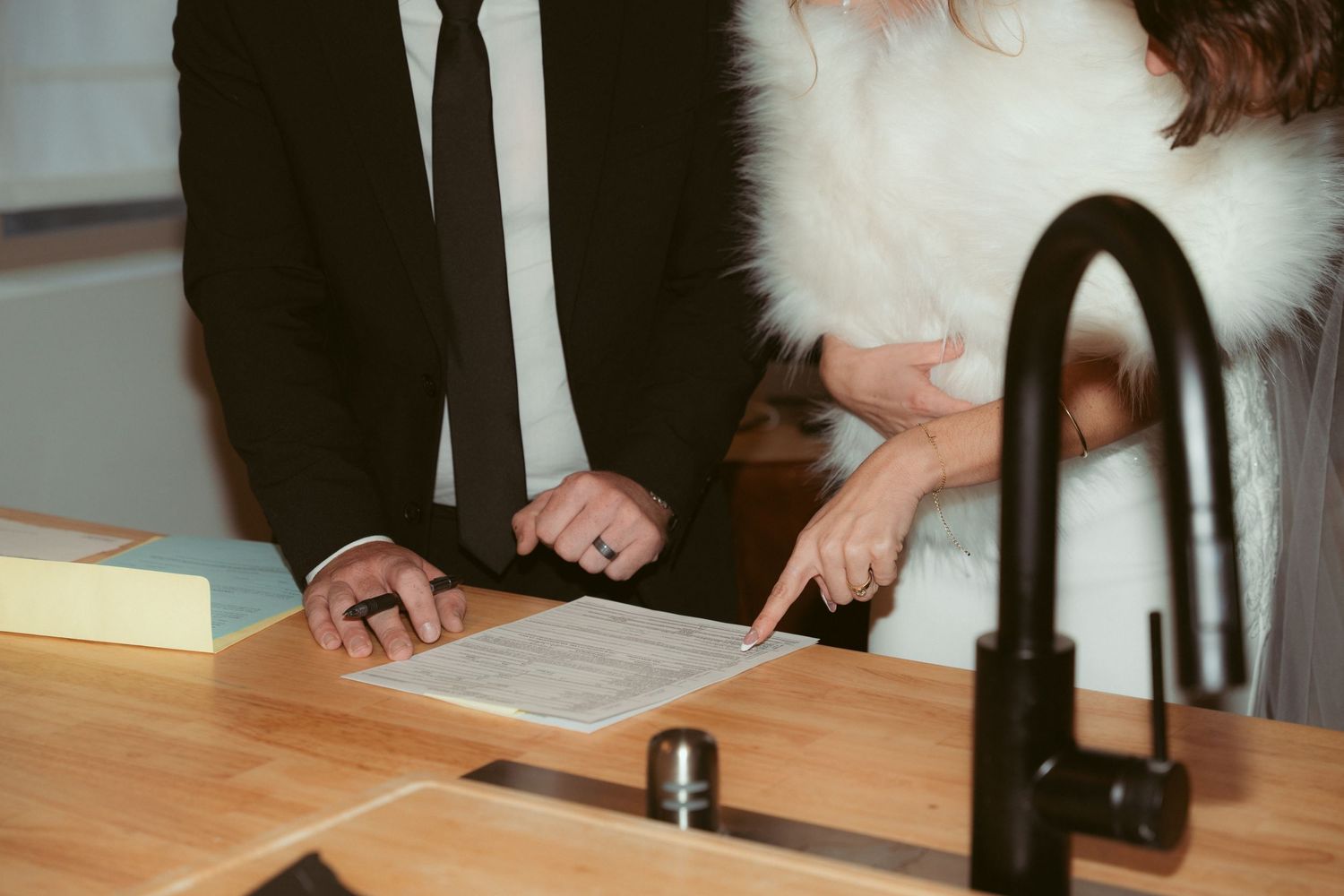 People examining paperwork at a kitchen counter with a modern black faucet.