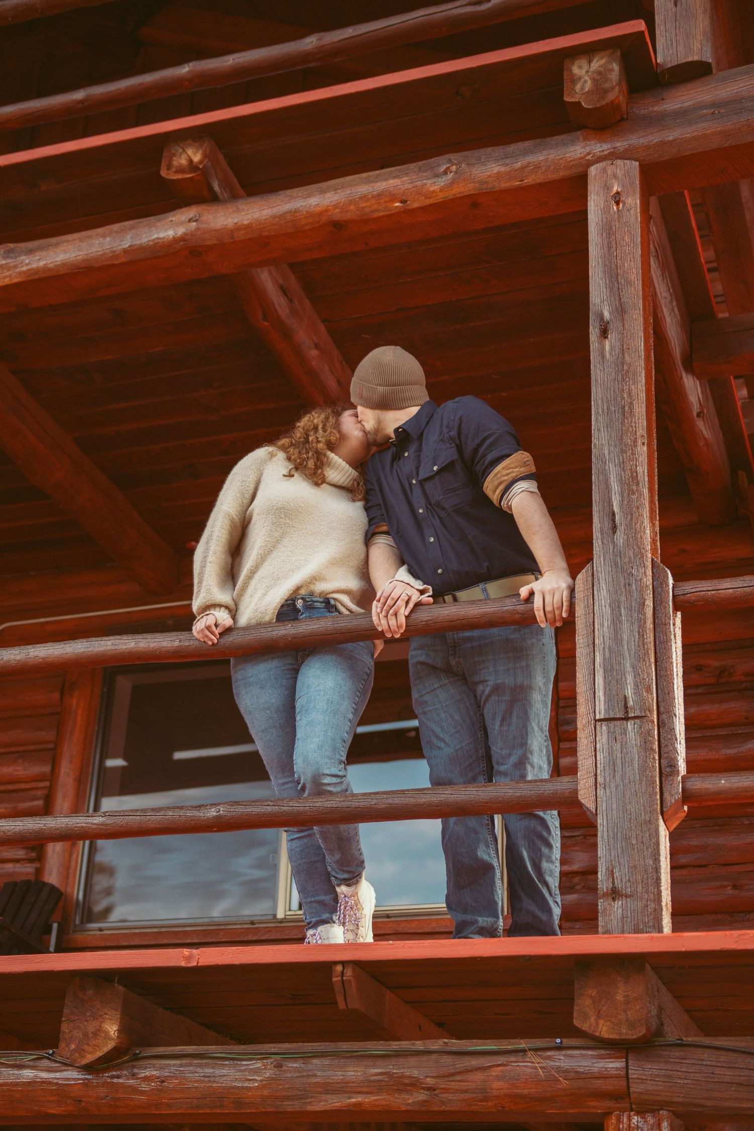 Two people sitting close together on a wooden deck with rustic beams.