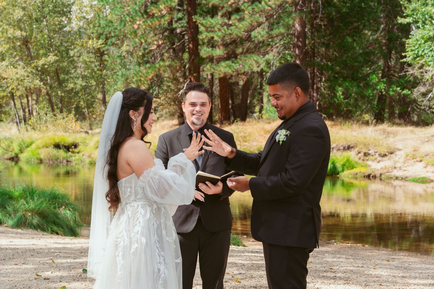 A wedding ceremony unfolds beside a tranquil lake surrounded by forest scenery.