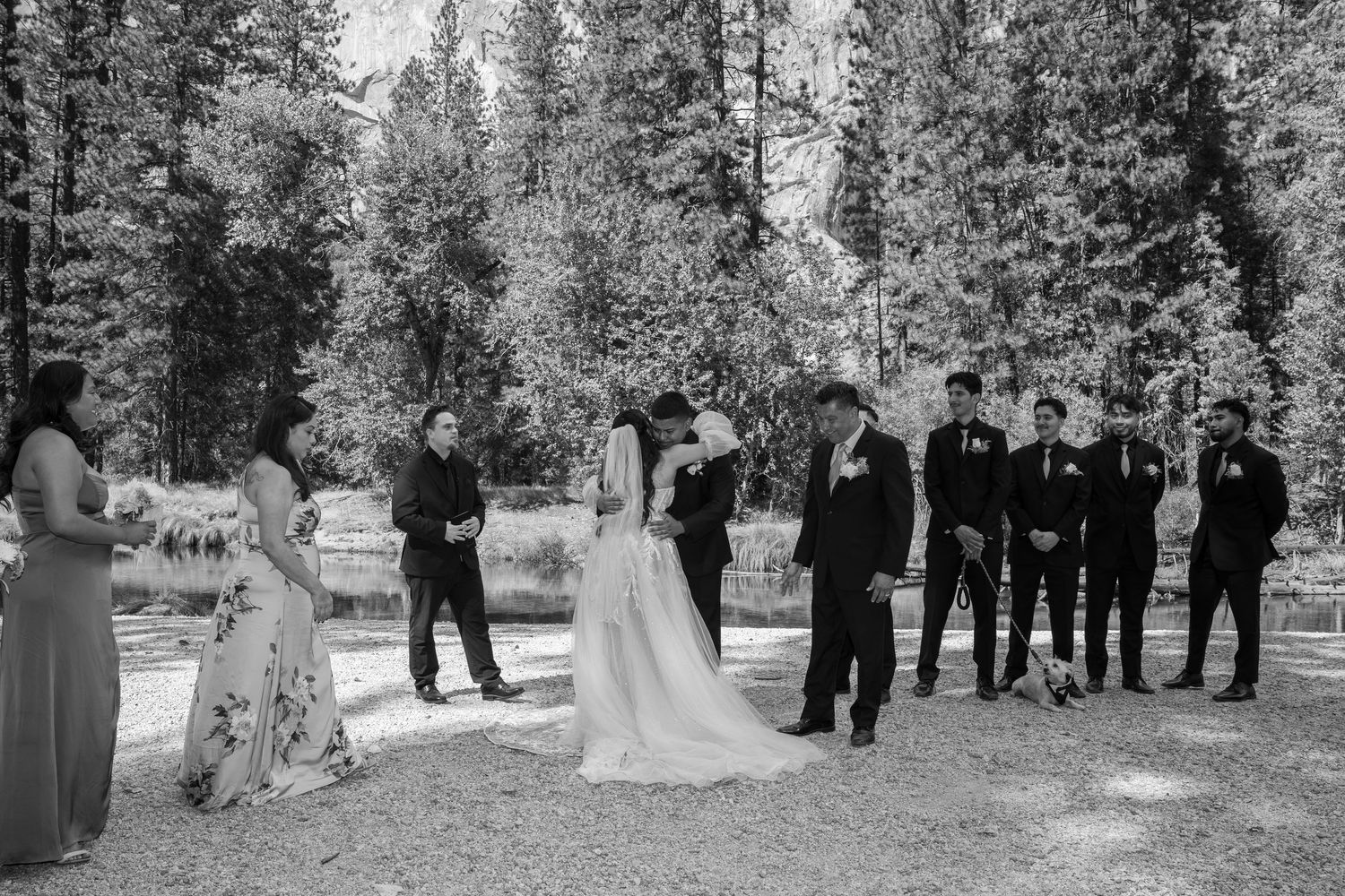 Black and white photo of wedding ceremony in a forest clearing with mountain backdrop.