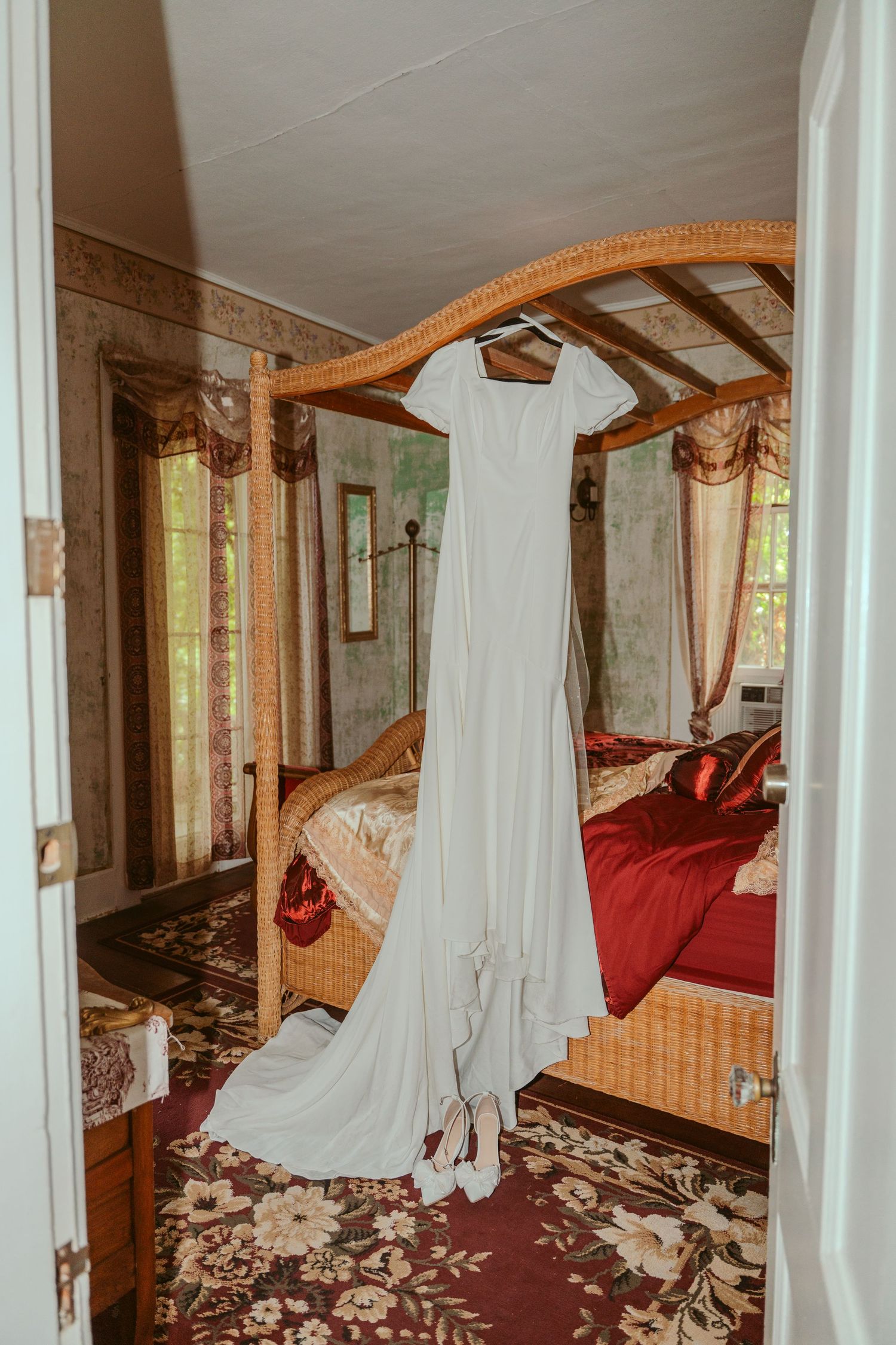 White wedding dress hanging in a bridal suite with ornate mirrors and decor.