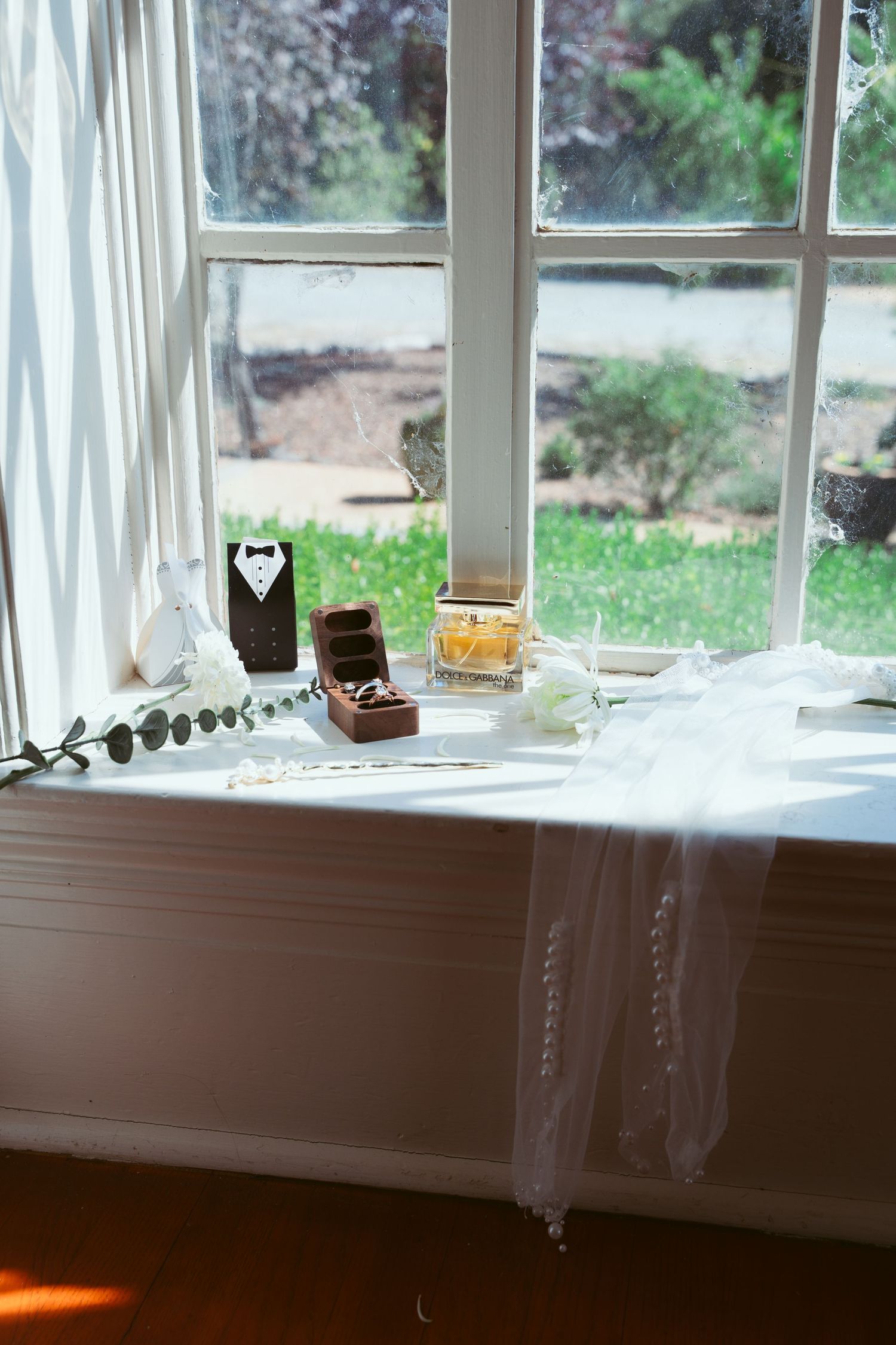 Sunlit window sill with white curtains and decorative elements creating a romantic atmosphere.