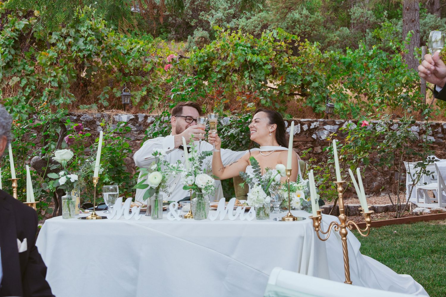 Elegant outdoor wedding reception tables set with white floral centerpieces.