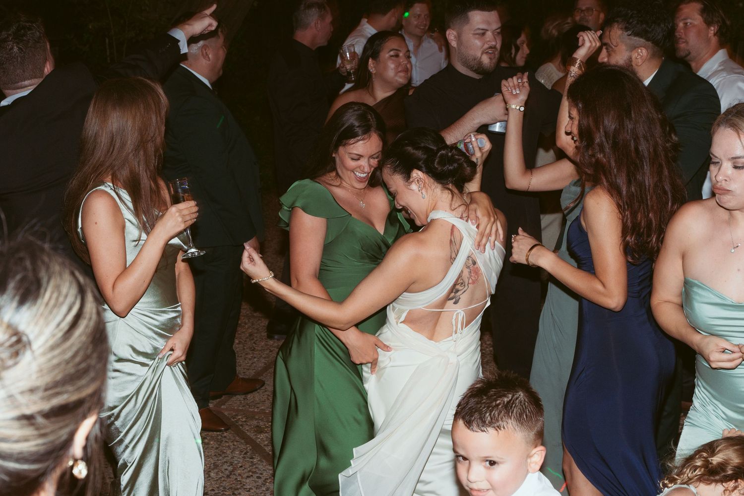 Wedding guests dancing and celebrating together on a lively dance floor at an evening reception.