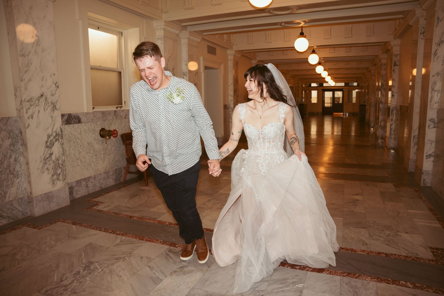 Wedding party walking through an illuminated indoor hallway with concrete walls.