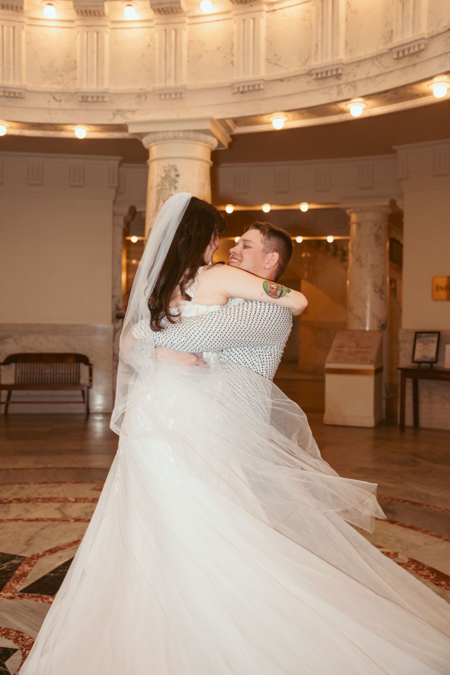 Elegant ballroom wedding dance with flowing white dress and ornate architectural details.