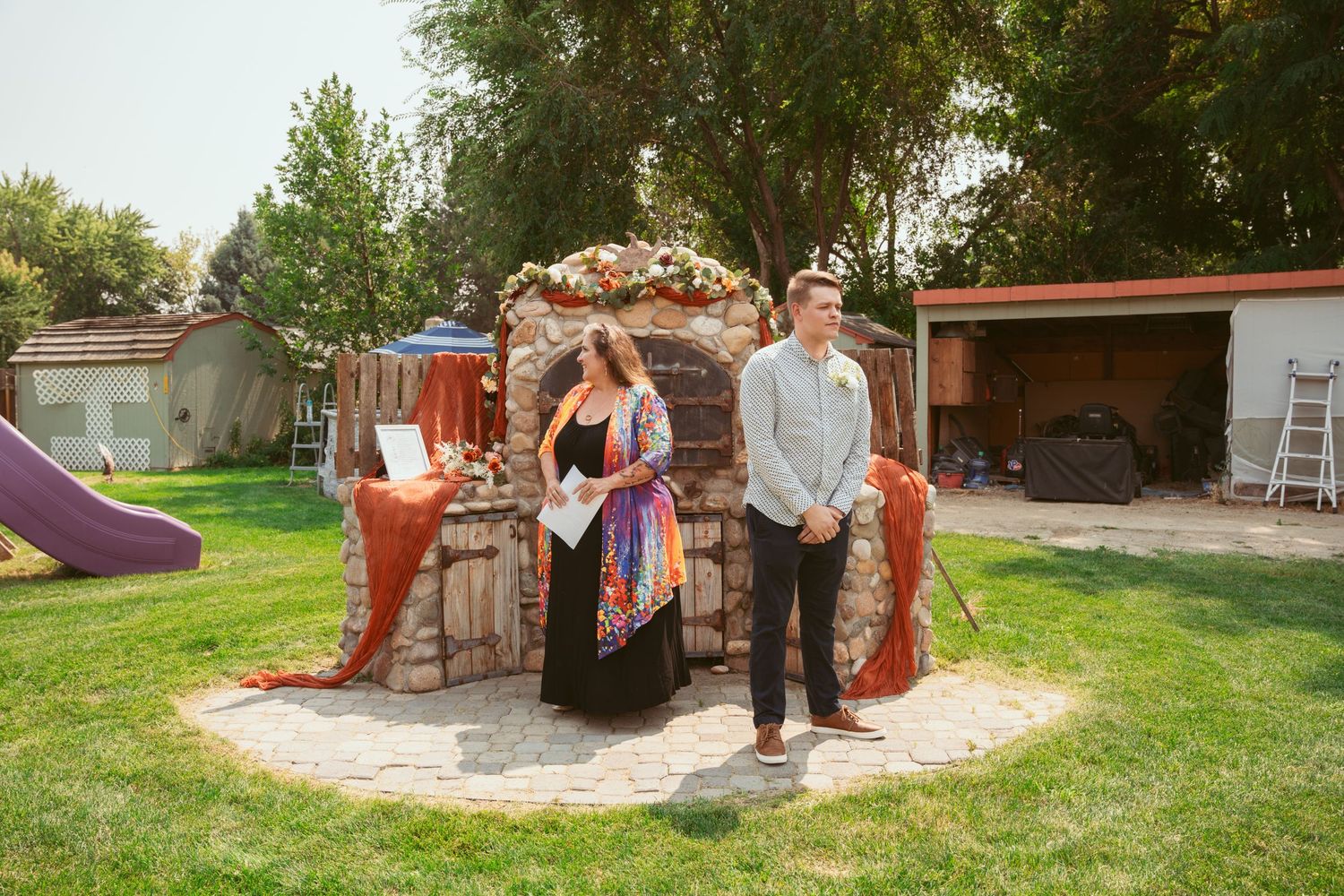 Wide view of an outdoor wedding venue with stone structures and grassy landscape.