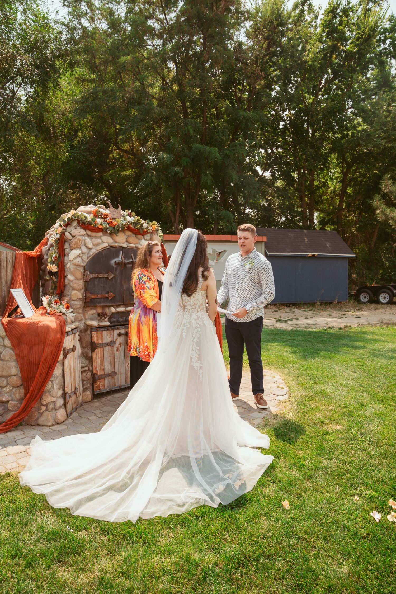 Wedding photo session in garden setting with stone wall backdrop and natural greenery.