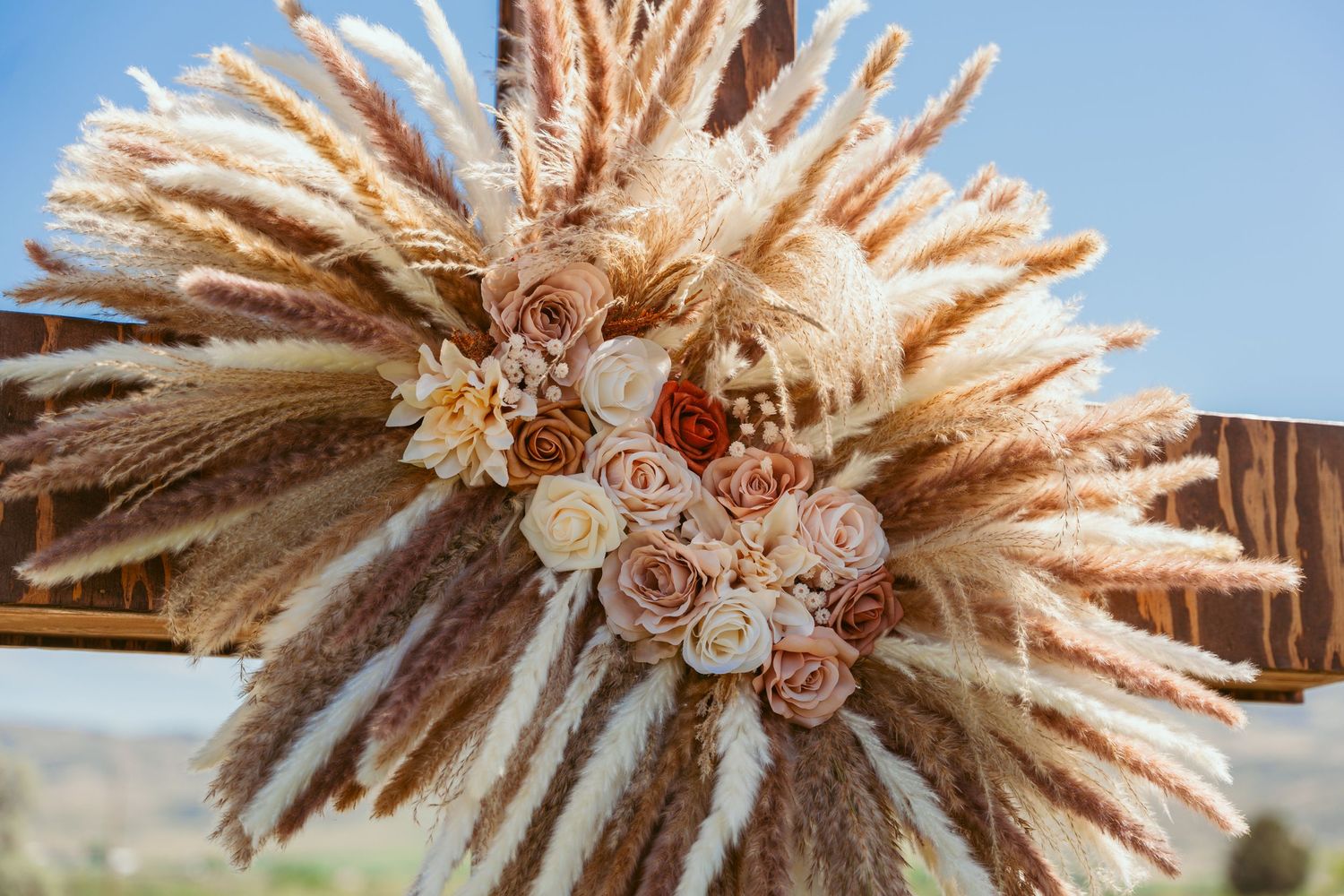 Close-up details of a boho-style floral arrangement with pampas grass and roses.