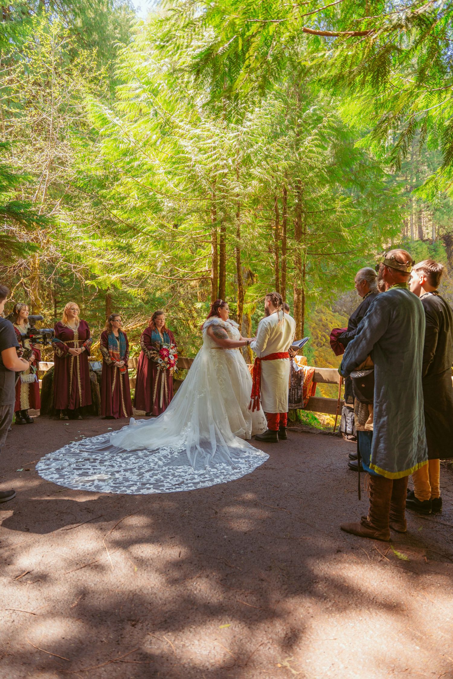 A panoramic view of a medieval-themed wedding ceremony taking place in a serene forest setting.