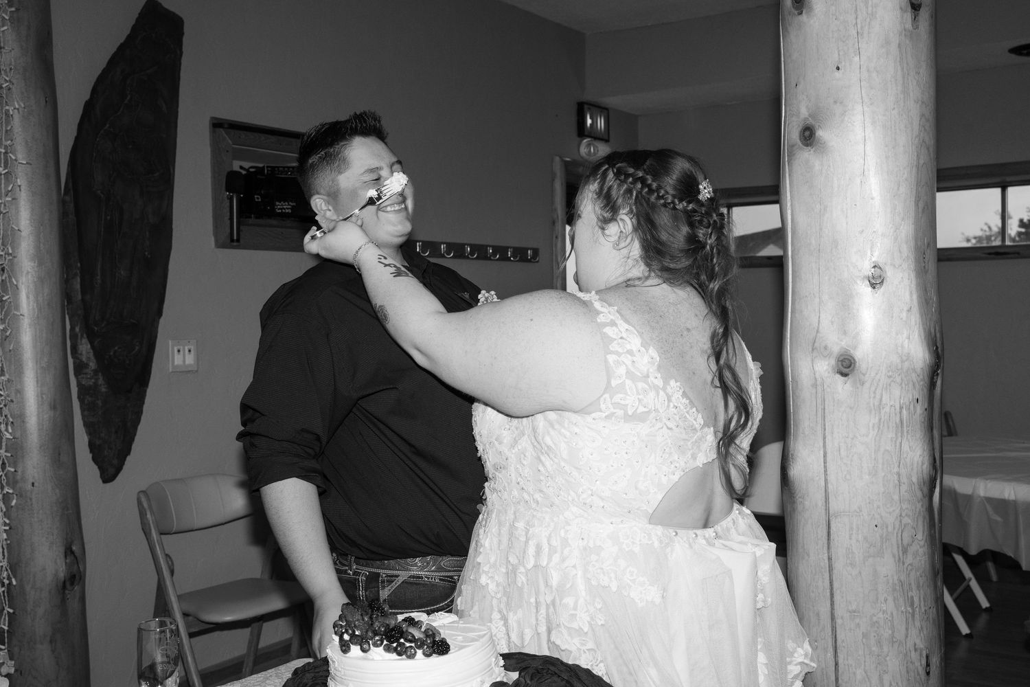Black and white photo of a couple playfully smearing cake on each other's faces.