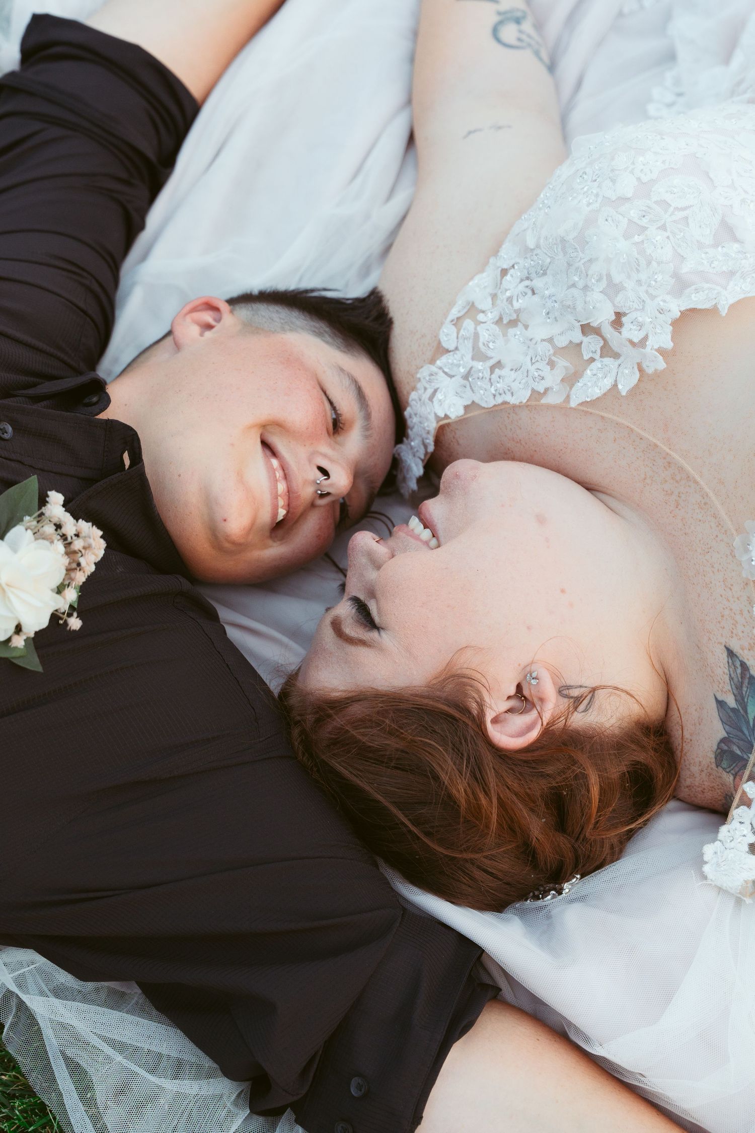 Romantic couple lying on grass during wedding photoshoot in color.