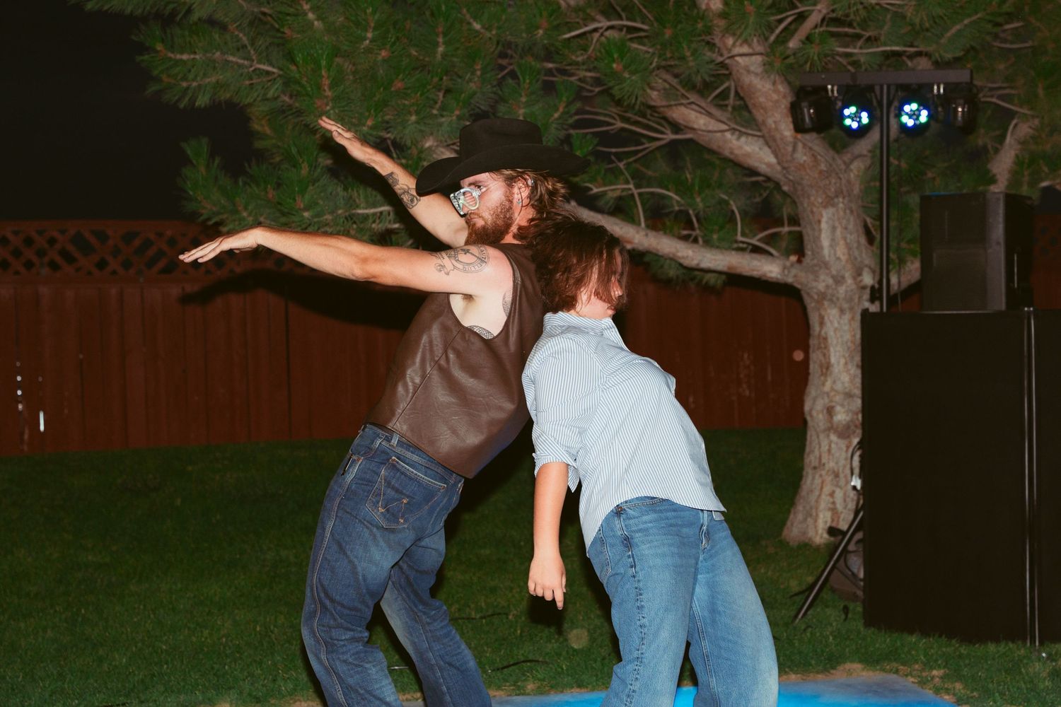 Two people dancing energetically outdoors at night with dramatic poses.